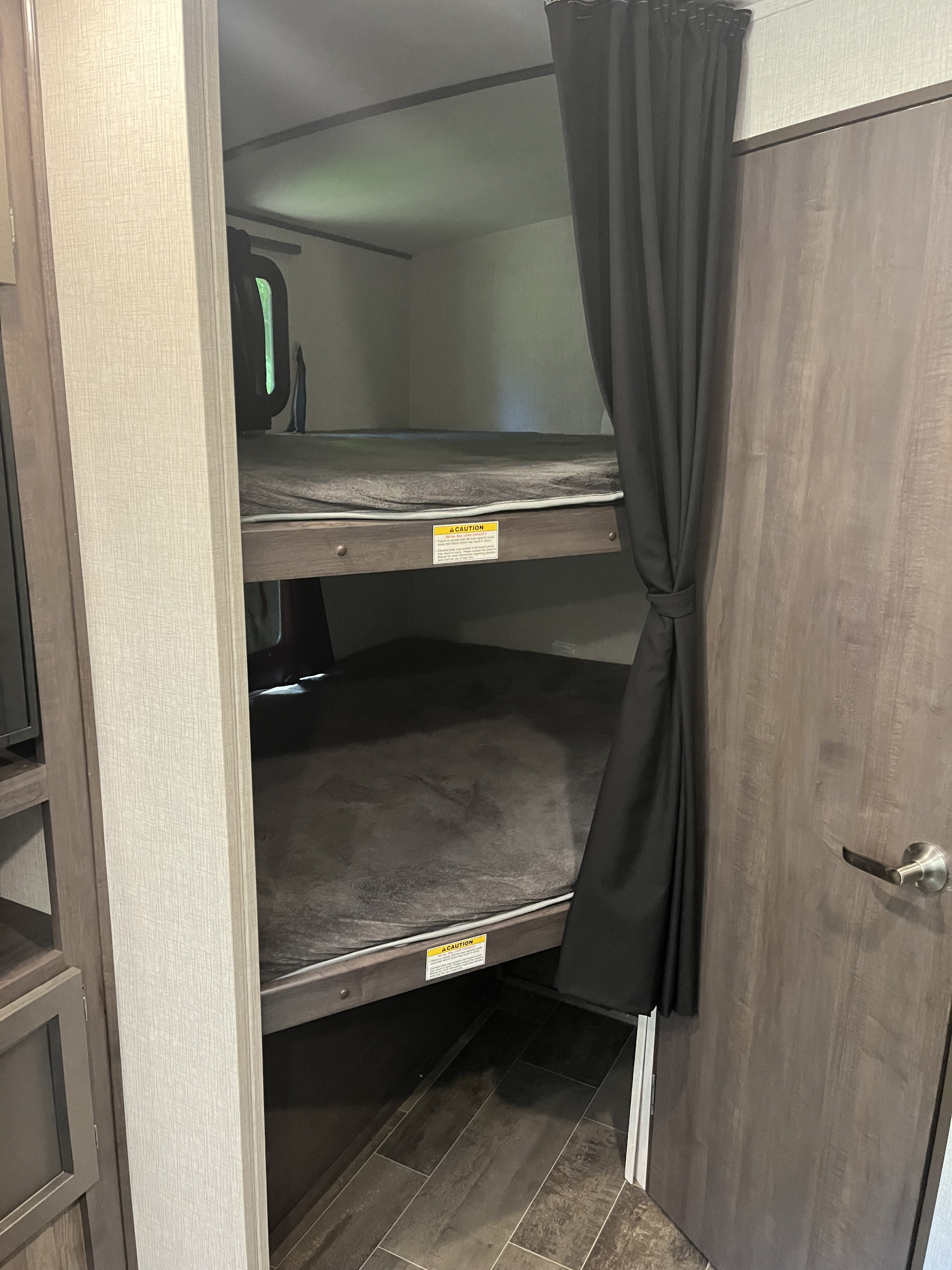 RV rental interior showcasing two bunk beds with privacy curtains, a common feature for family camping trips.. Crossroads Sunset Trail 2020