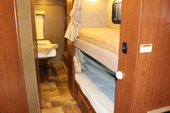 This rv rental features built-in bunk beds on the right, and a bed further down the hallway, offering multiple sleeping areas.. Thor Chateau 2016