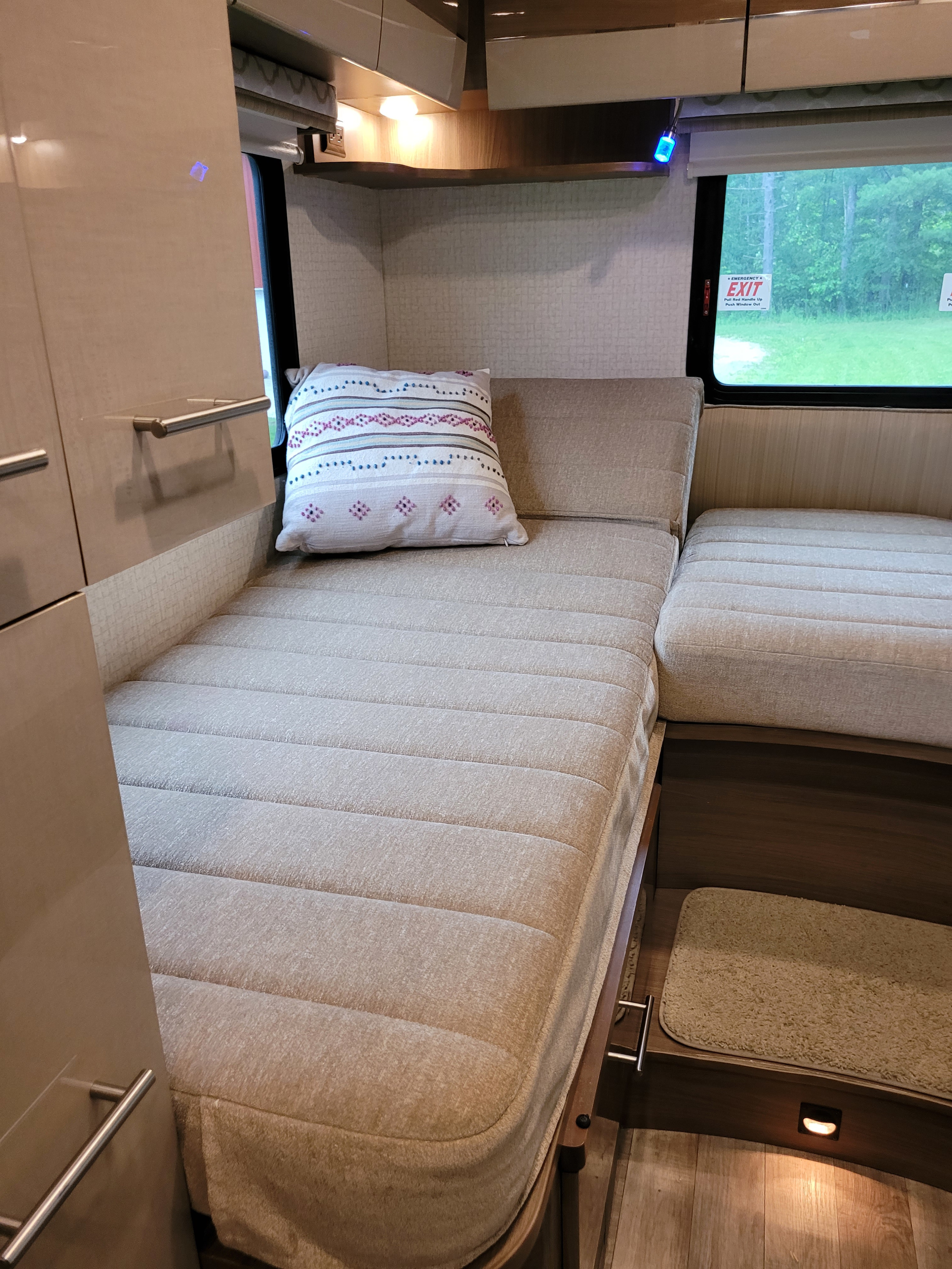Experience comfort in this RV rental's inviting interior: plush bed/seating, modern cabinetry, and large window offering outdoor views.. Winnebago View 2017