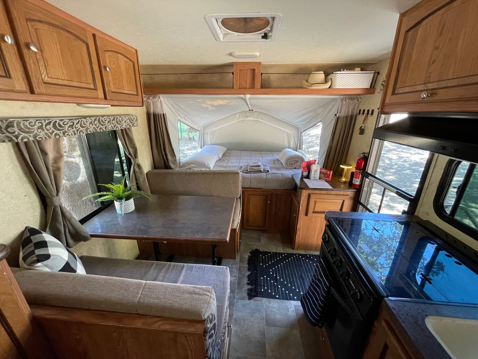 This clean RV rental interior features a comfortable pop-out bed, dinette area, and compact kitchen.. Forest River Flagstaff Shamrock 2015