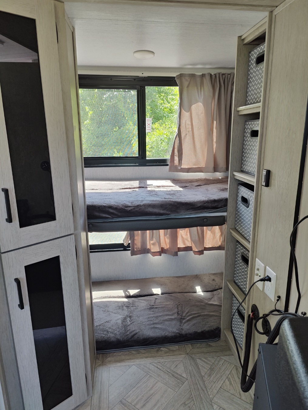 Cozy RV rental interior showing two bunk beds with blankets, a window view, and built-in storage.. Forest River Salem Cruise Lite 2024
