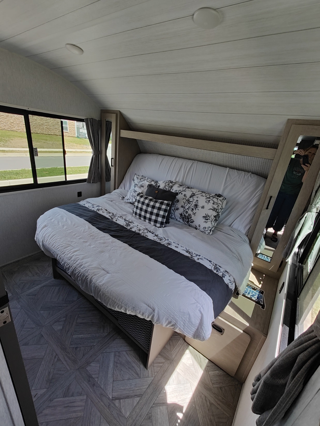 Cozy RV rental bedroom with a large bed, patterned pillows, windows showing the outdoors, and light wood interior.. Forest River Salem Cruise Lite 2024