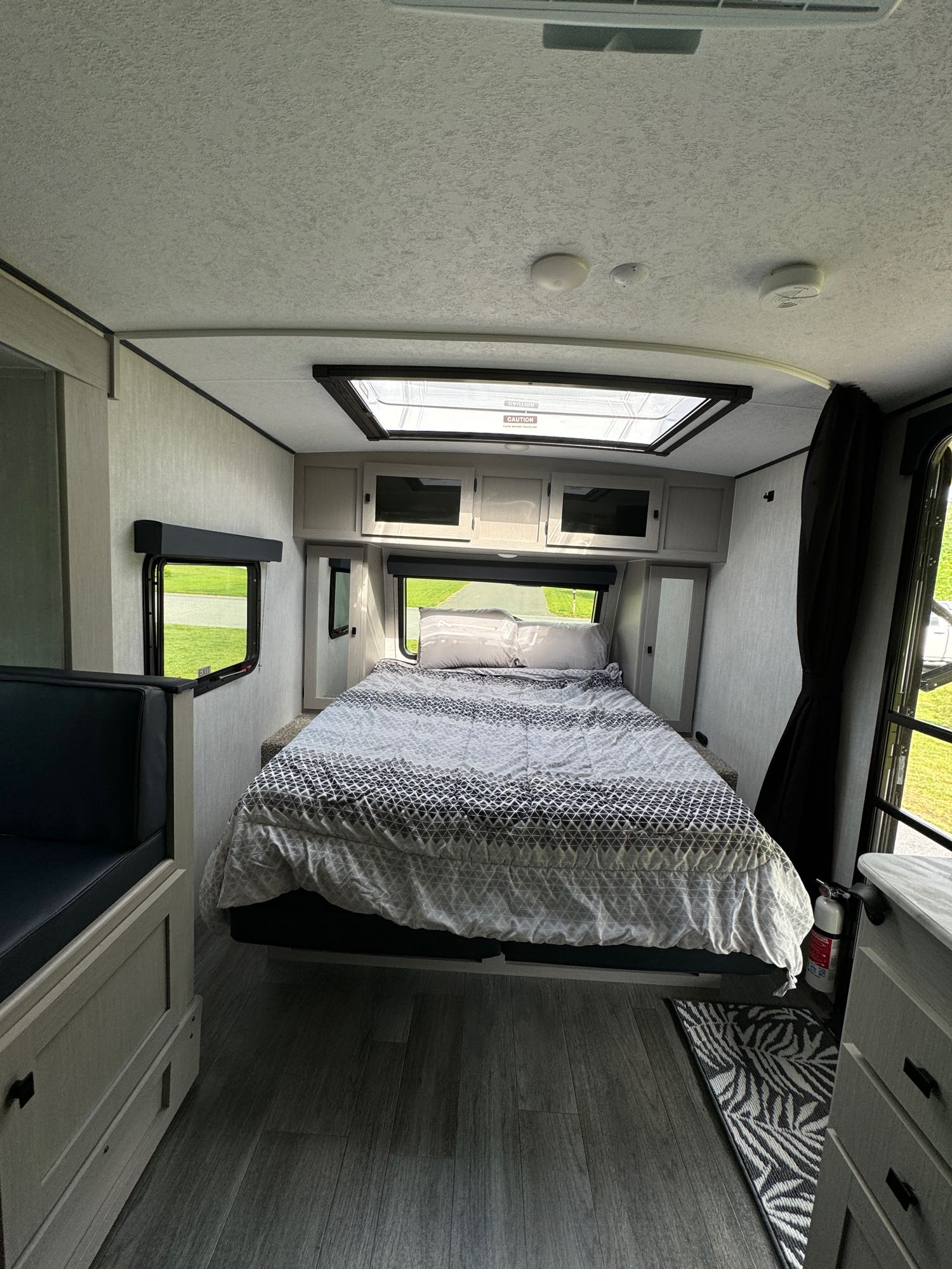 Inside a modern **rv rental**, a compact bedroom with a patterned bed, skylight, and dinette hints at adventure.. Forest River Coachmen Apex Nano 208BHS 2024