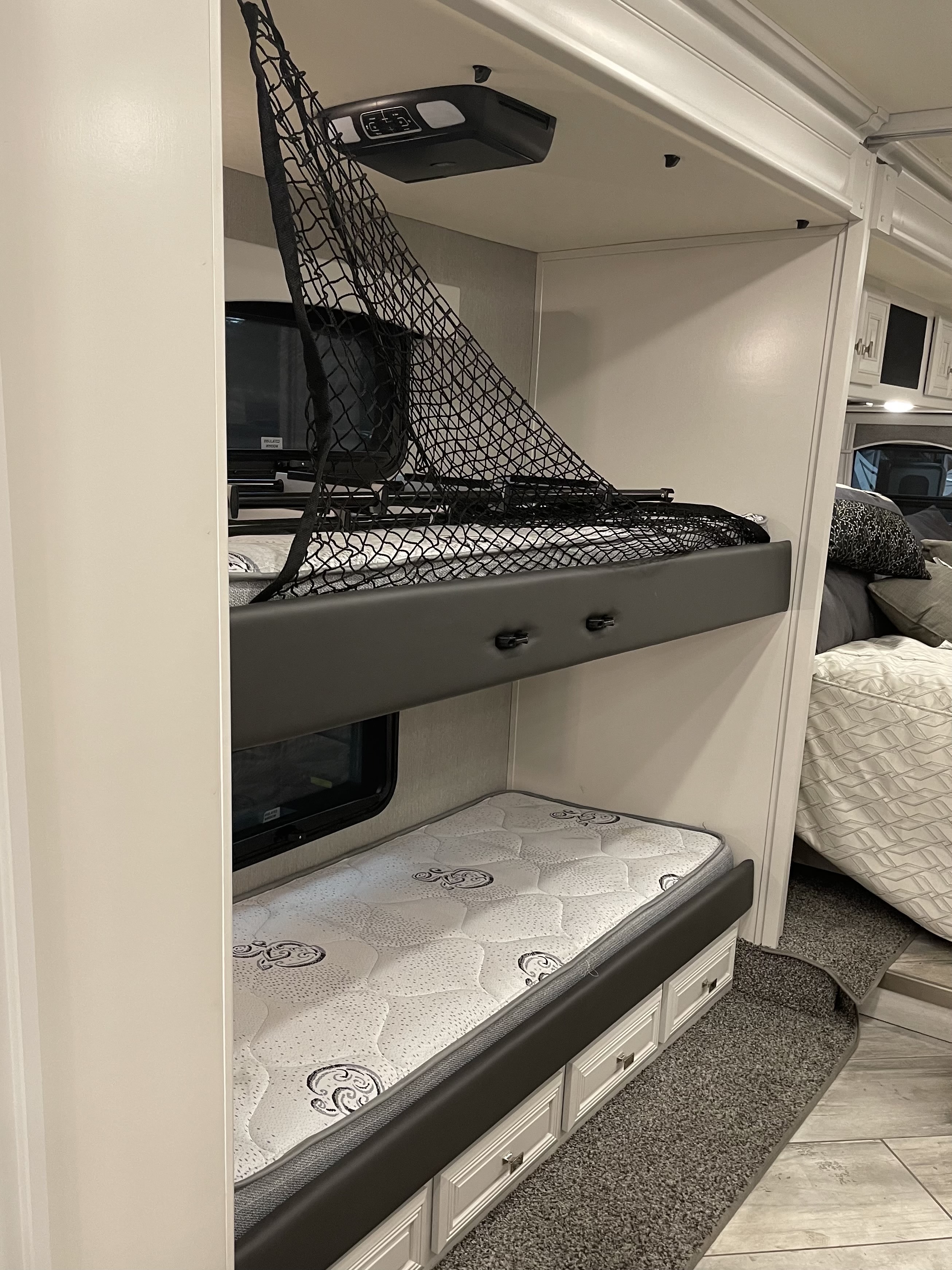 RV rental bunk beds with safety net, lower mattress, and storage drawers. Compact and family-friendly RV interior.. Fleetwood Discovery 2021