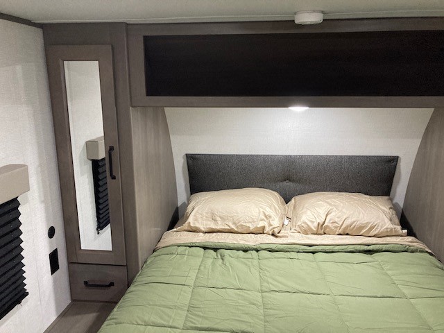 Inside an RV rental: a compact bedroom featuring a comfortable bed, mirrored wardrobe, and overhead storage.. Grand Design Transcend Xplor 2024