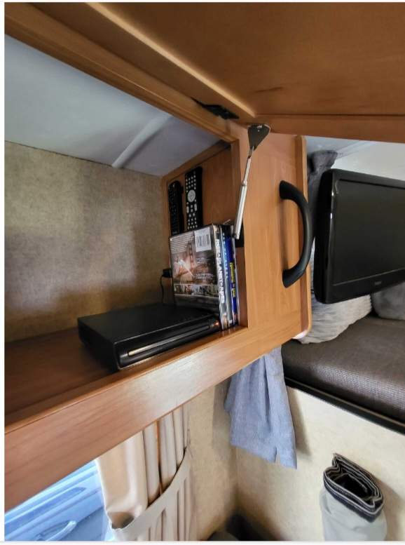 RV rental entertainment: compact built-in system with DVD player, remotes, & TV, nestled in a wooden cabinet.. Thor Majestic 2013