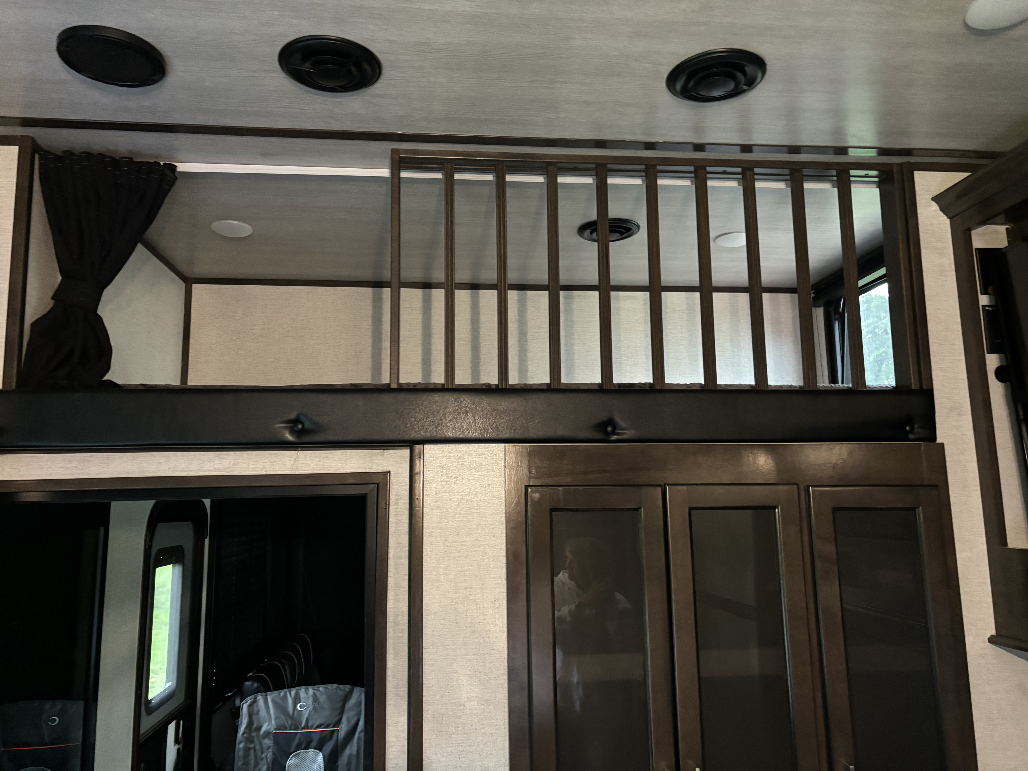 Spacious RV rental interior highlights a practical loft sleeping area with safety rails, ceiling vents, and lower cabinets.. Dutchmen Voltage 2022