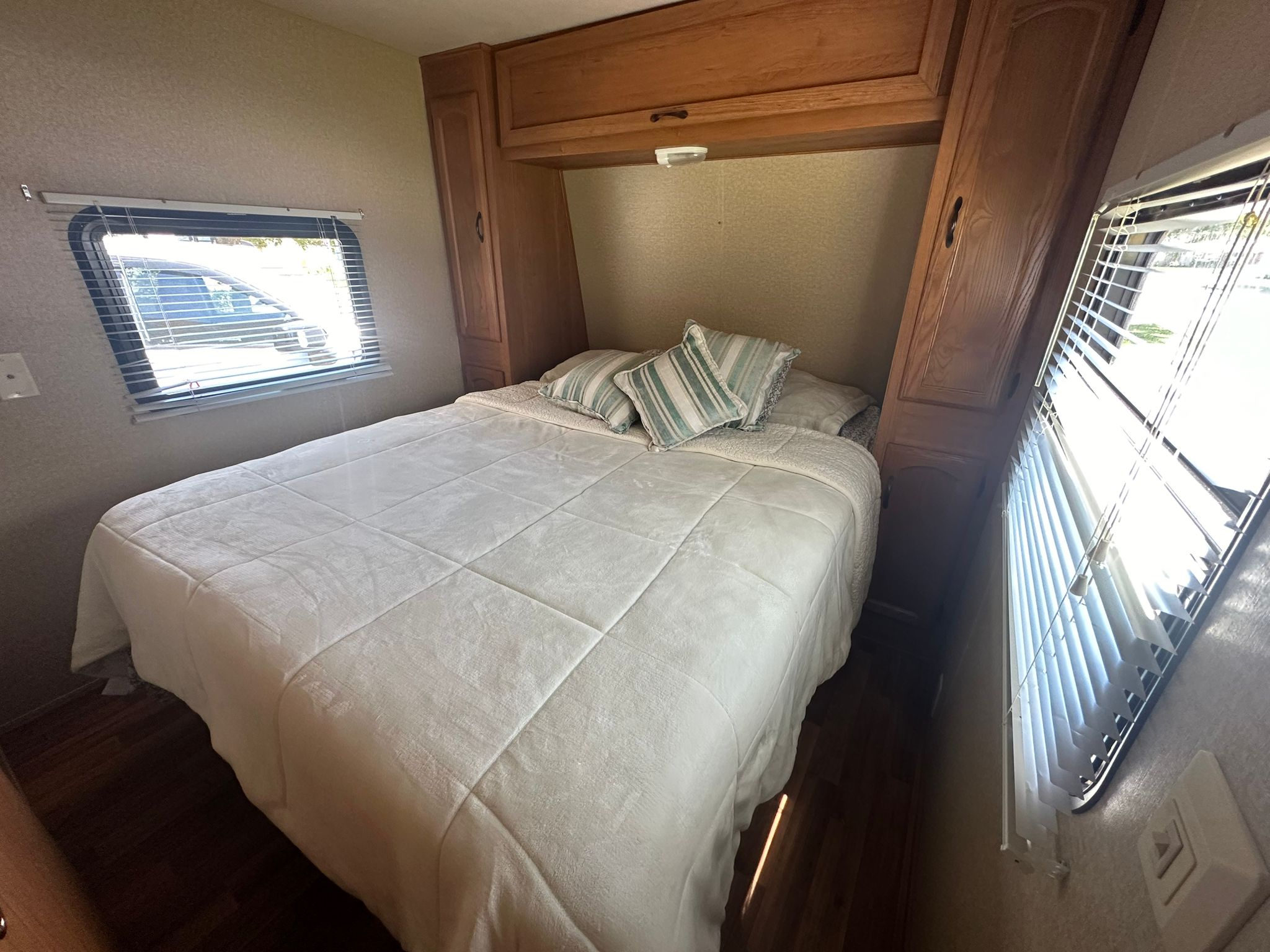 Spacious RV rental bedroom featuring a queen bed, abundant storage, and large windows with blinds. Comfort on the road.. Forest River Salem Cruise Lite 2010