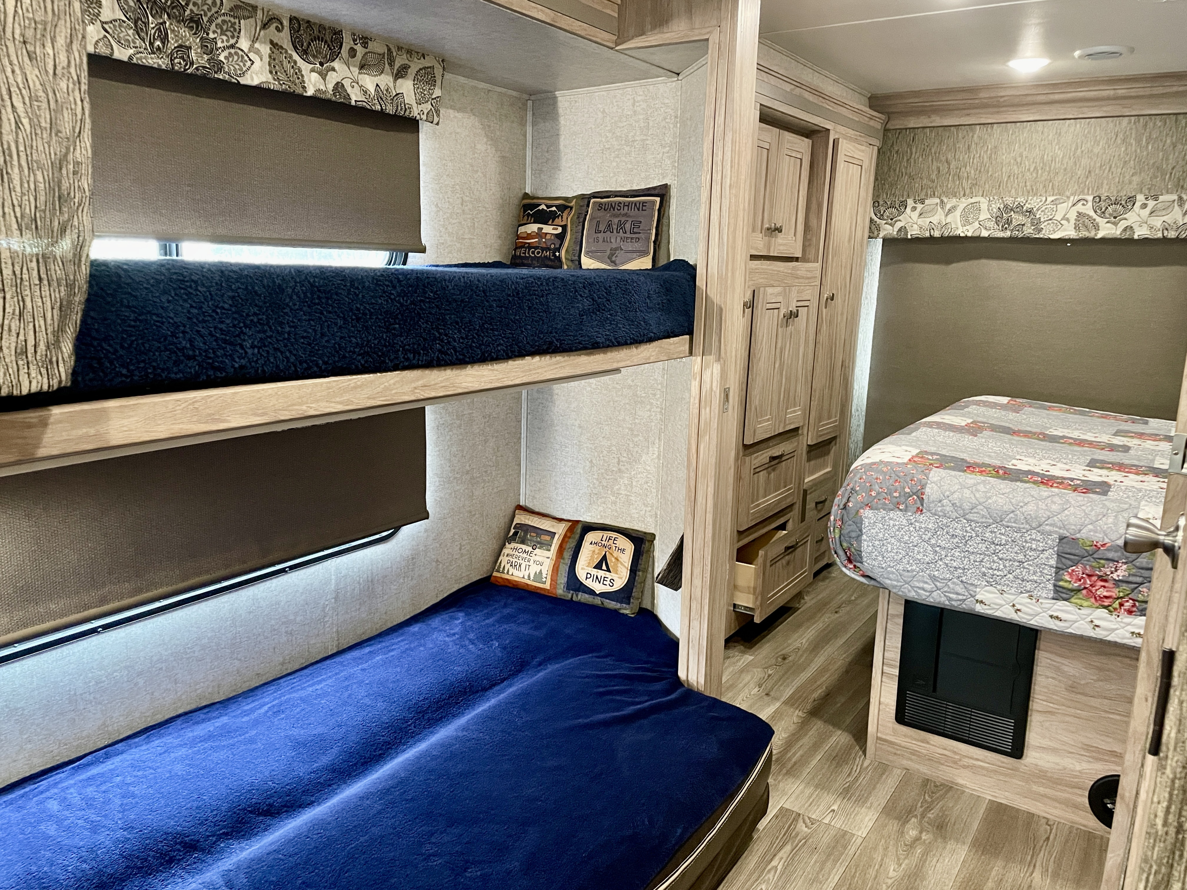 Spacious rv rental interior: cozy bunk beds with scenic pillows, a comfortable main sleeping area, and ample wood cabinets.. Forest River Forester 2017