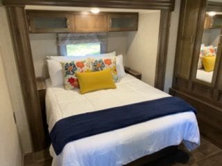 Comfortable RV rental bedroom with a neatly made bed, overhead storage, and mirrored closet. Ideal for travel or vacation.. Forest River Palomino Puma 2020