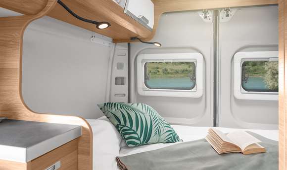 RV rental interior: Comfortable camper bedroom with bright lighting, a book, and scenic lake views for travel.. Knaus BOXLIFE 540 2024