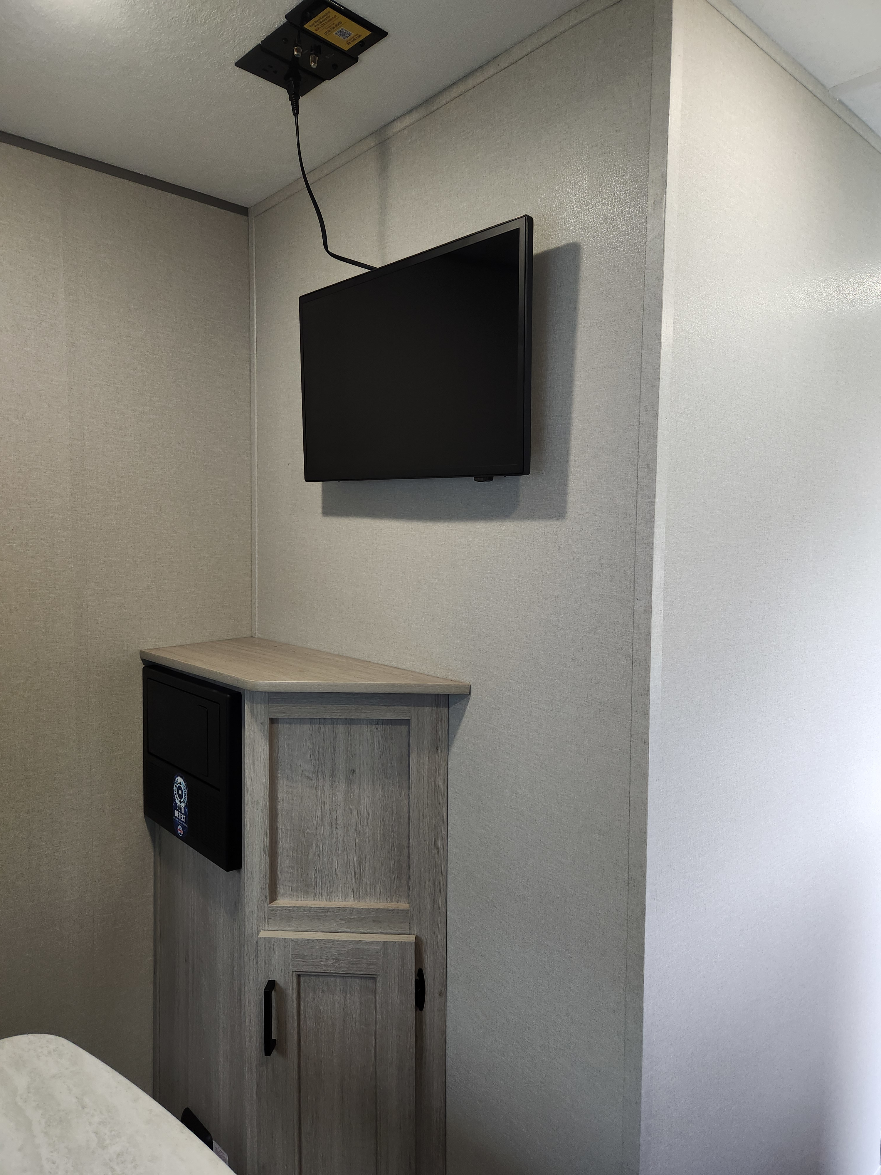 RV rental compact living space: wall-mounted TV, ceiling power, and a corner cabinet with a black control panel.. Forest River Aurora Aurora Light 2024