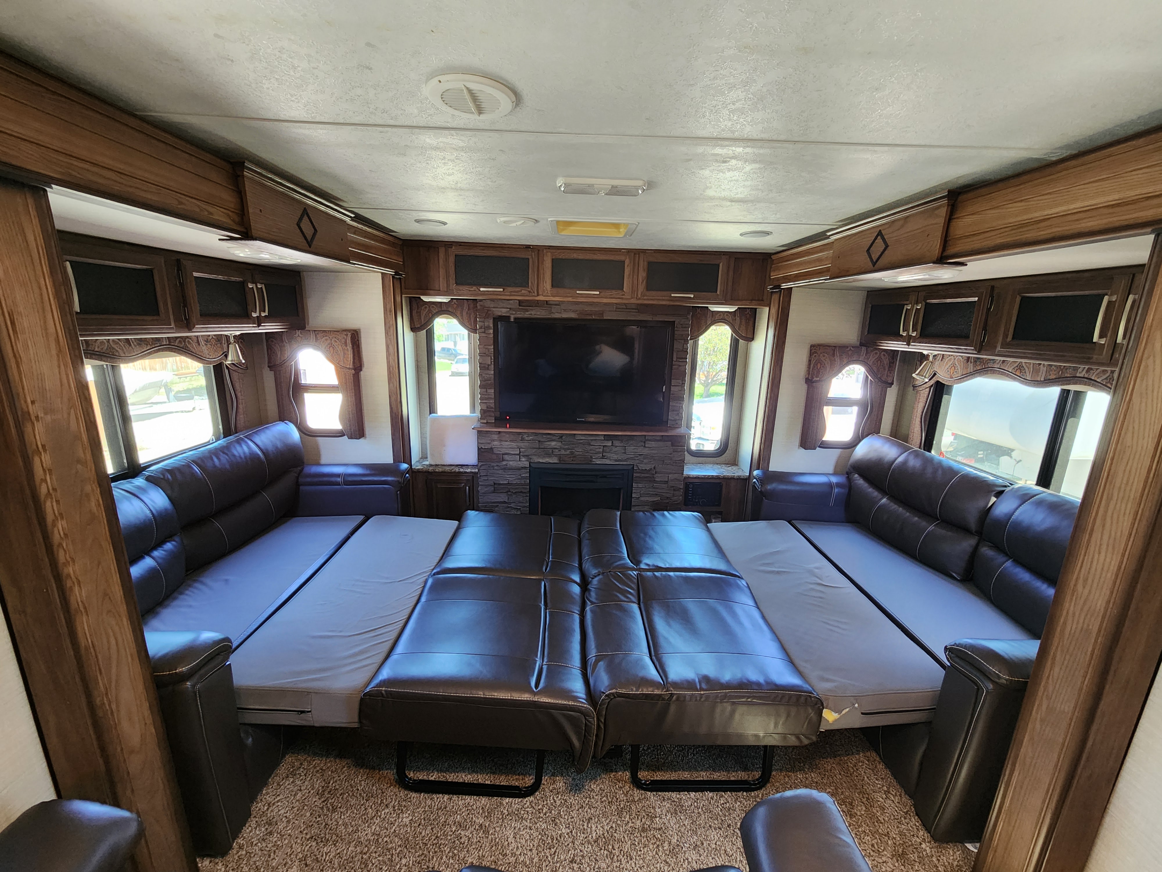 Spacious RV rental interior with sofas configured as beds, a large TV, and fireplace. Comfortable living area.. Keystone RV Cougar 2017