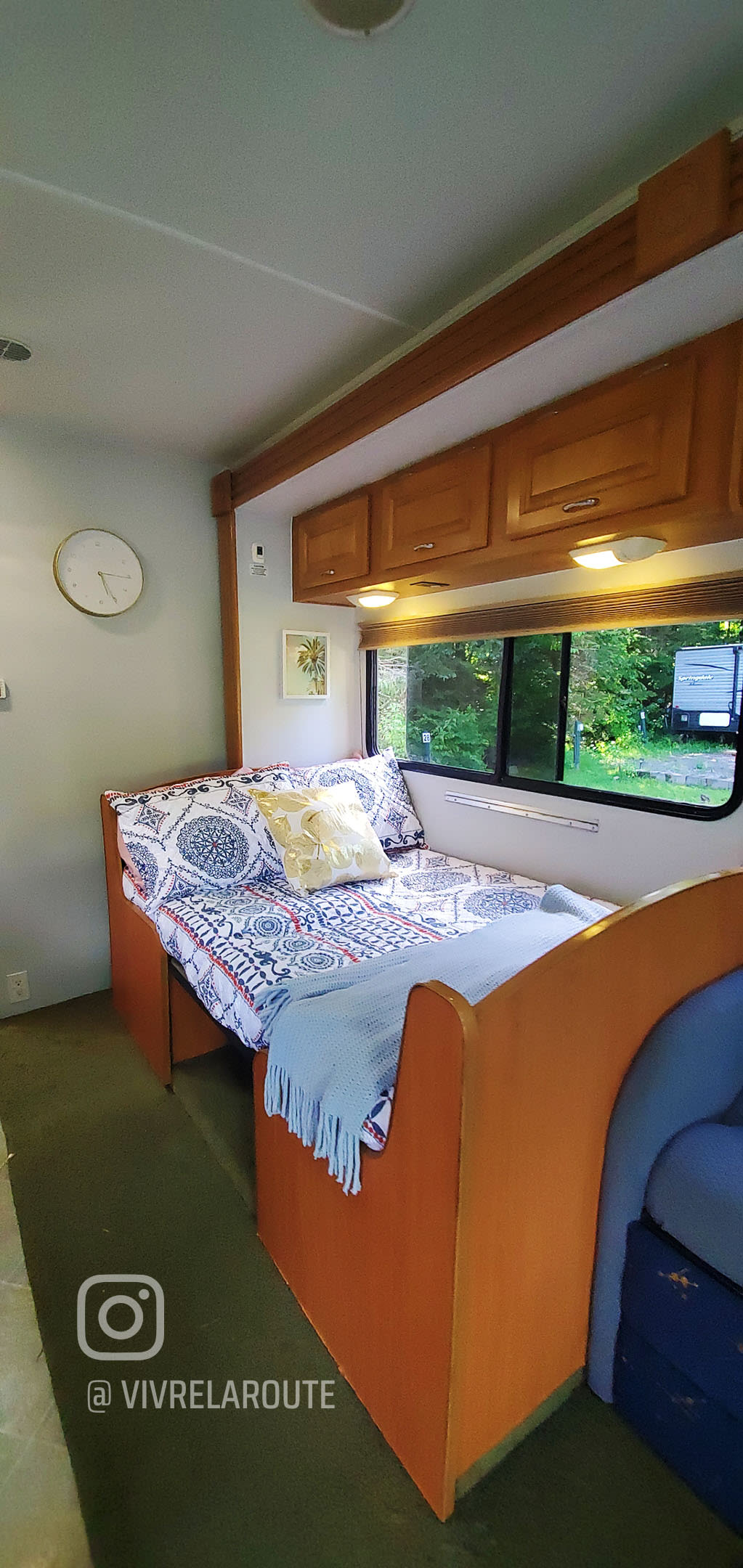 Cozy RV rental interior features a comfortable bed/dinette with patterned bedding, overhead cabinets, and a scenic window view for travel.. Coachmen Freelander Deluxe/Premier 2005