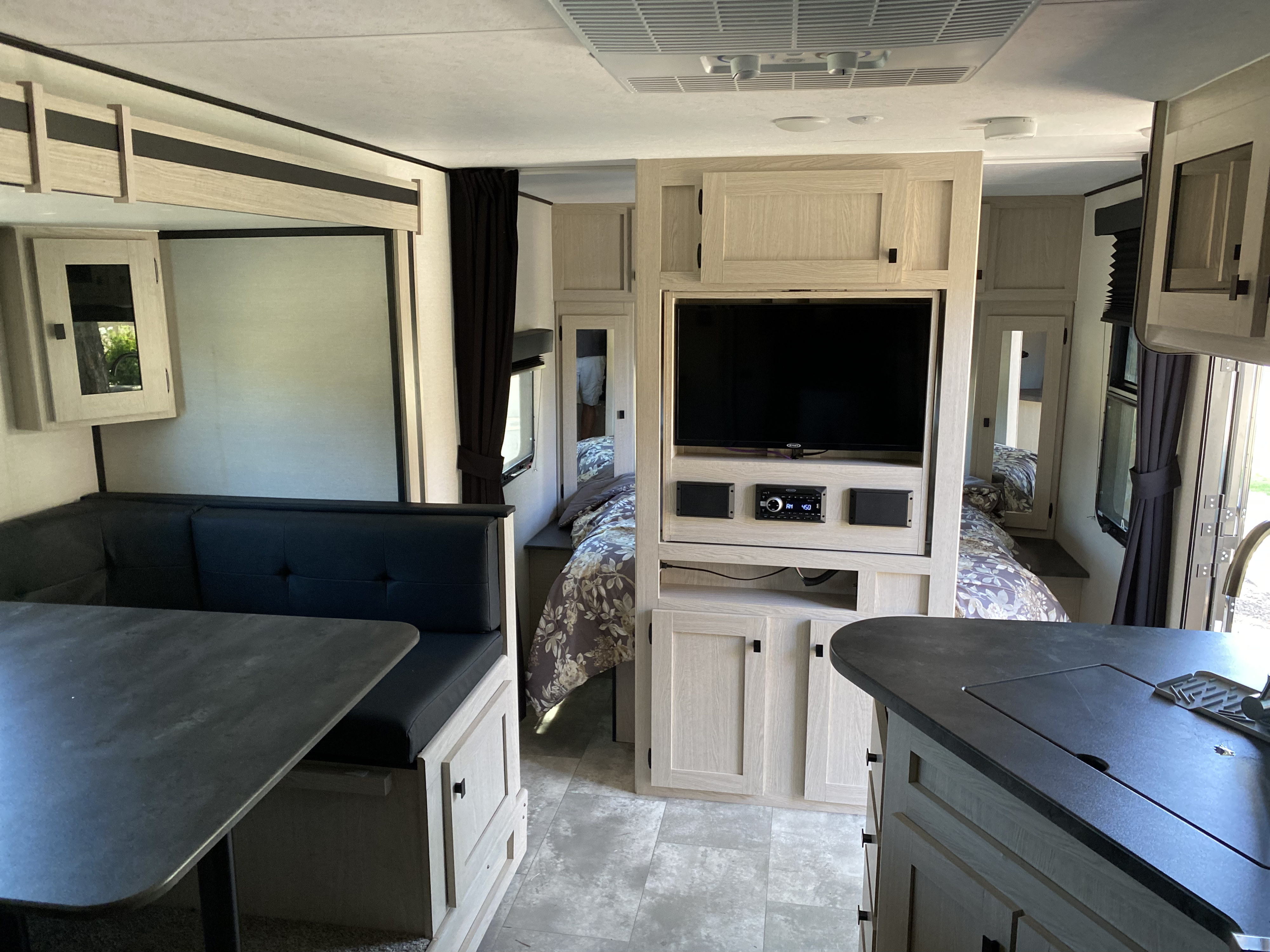 Spacious RV rental interior with dining area, TV, and cozy bed. Ideal for travel adventures.. Coachmen Apex 2024