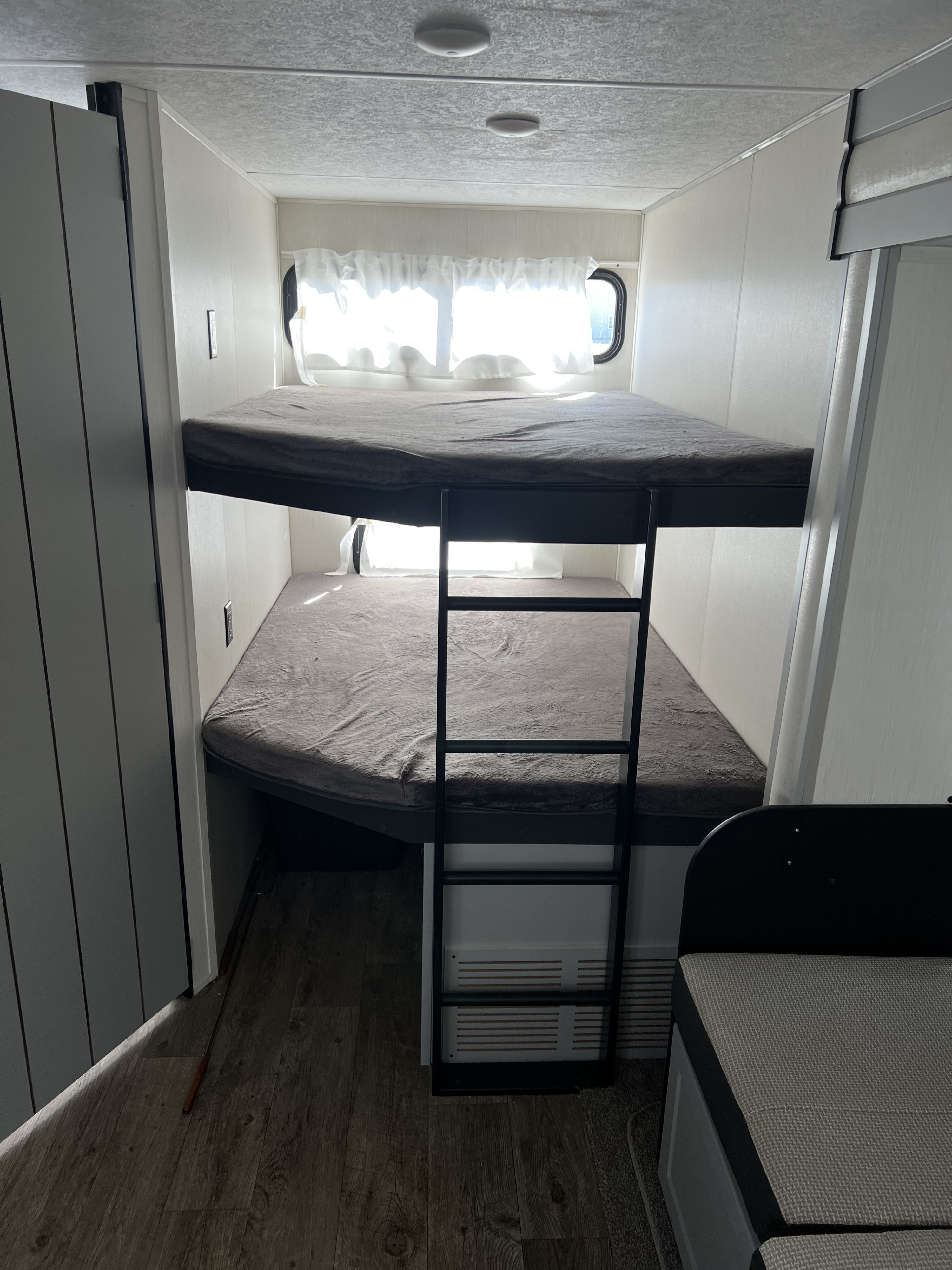 RV rental: Cozy interior featuring two bunk beds with grey mattresses, a black ladder, and bright windows.. Forest River Vibe 2021