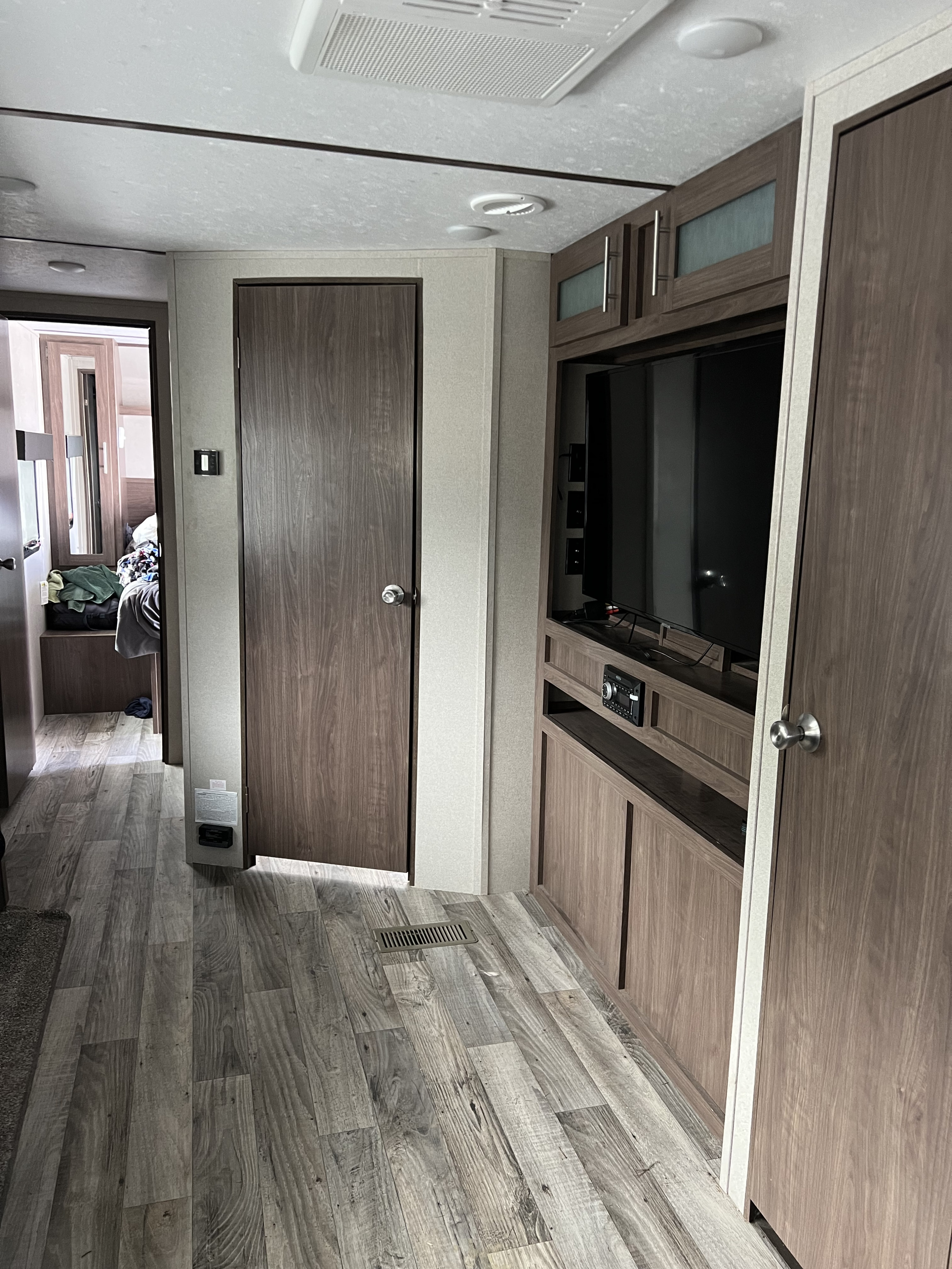 RV rental interior: A modern living space with wood-look flooring, TV, cabinets, and a hallway to the sleeping area.. Keystone RV Hideout Luxury 2020
