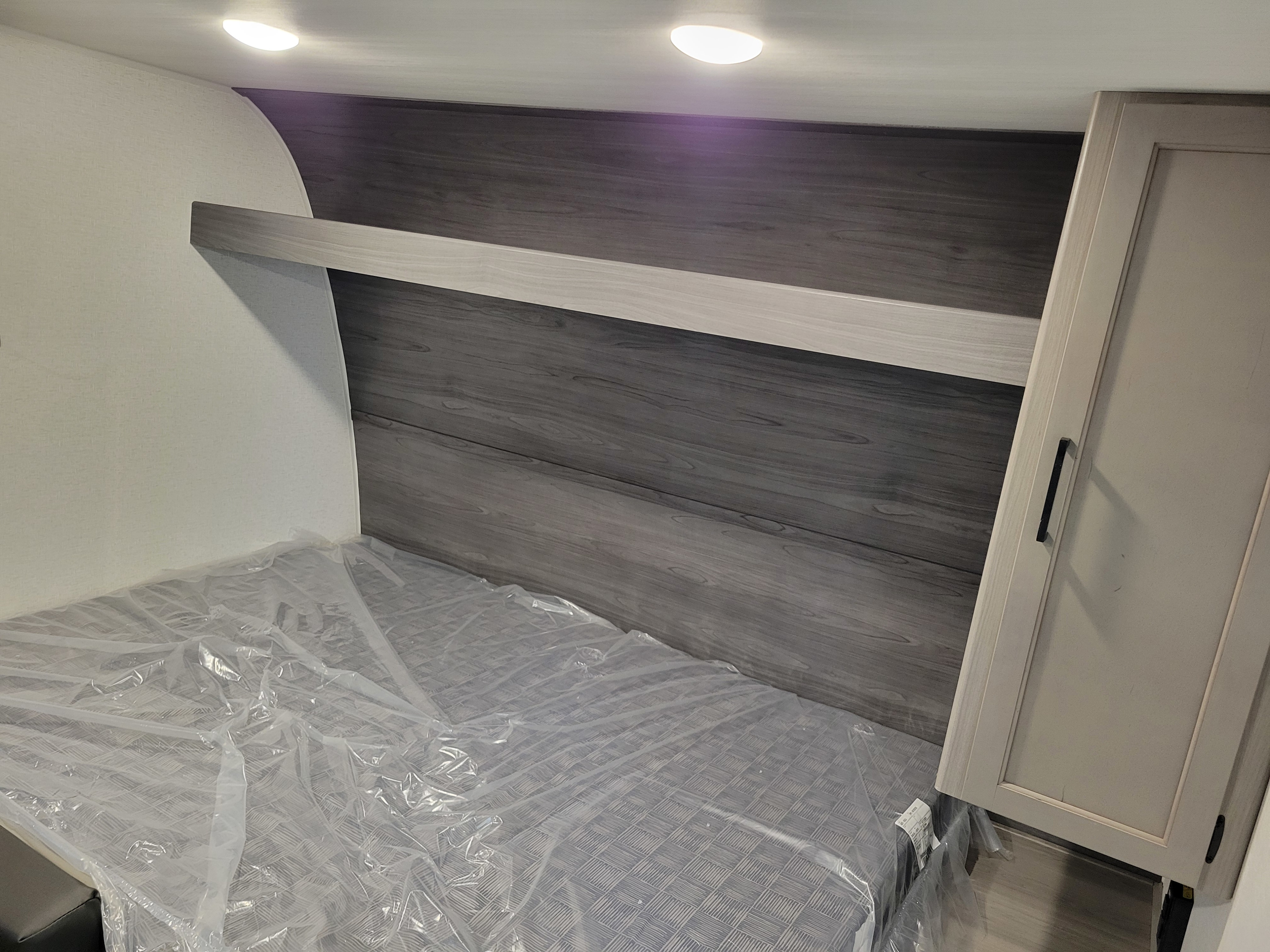 RV rental bedroom with new mattress, modern headboard, and cabinet for comfortable sleeping.. Keystone RV Hideout Sport 2024