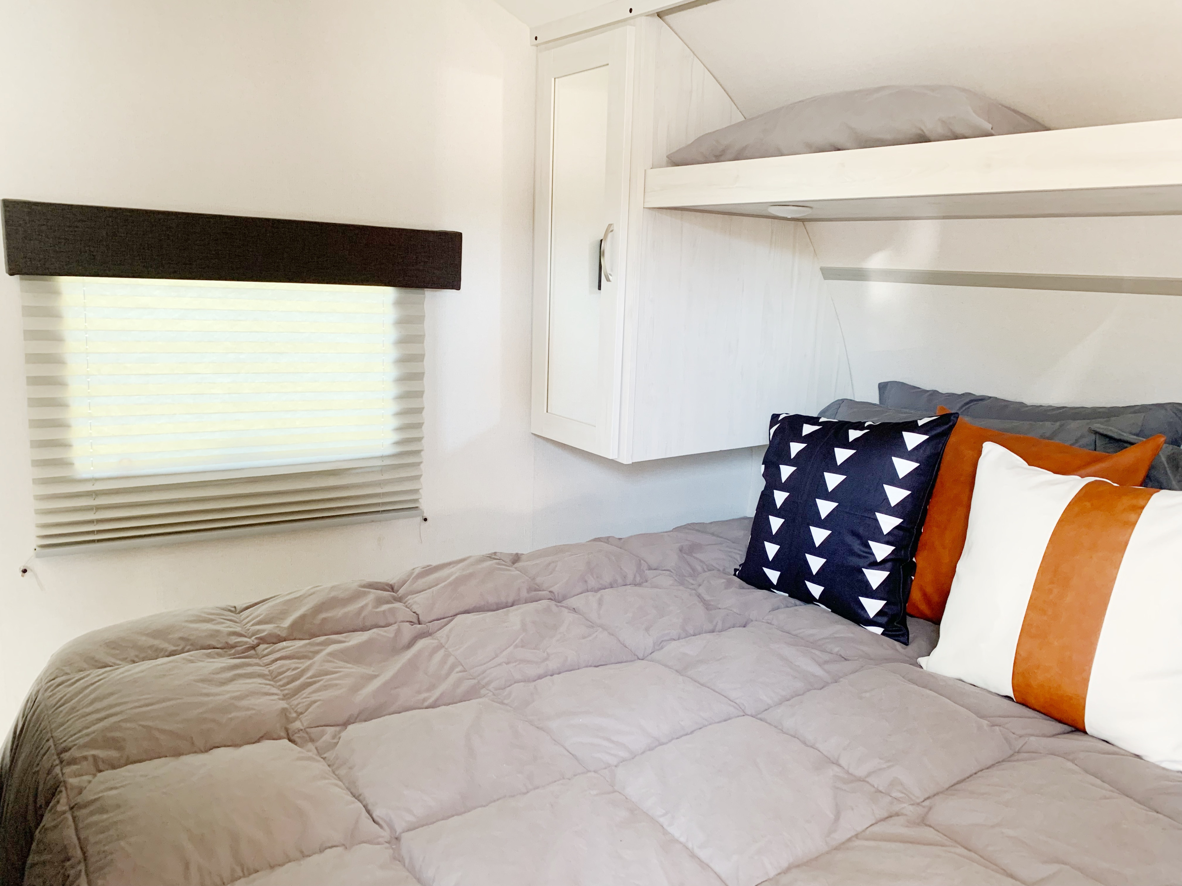 RV rental interior featuring a cozy bedroom with a quilted comforter, decorative pillows, and an upper bunk.. Tracer 24 DBS 2022