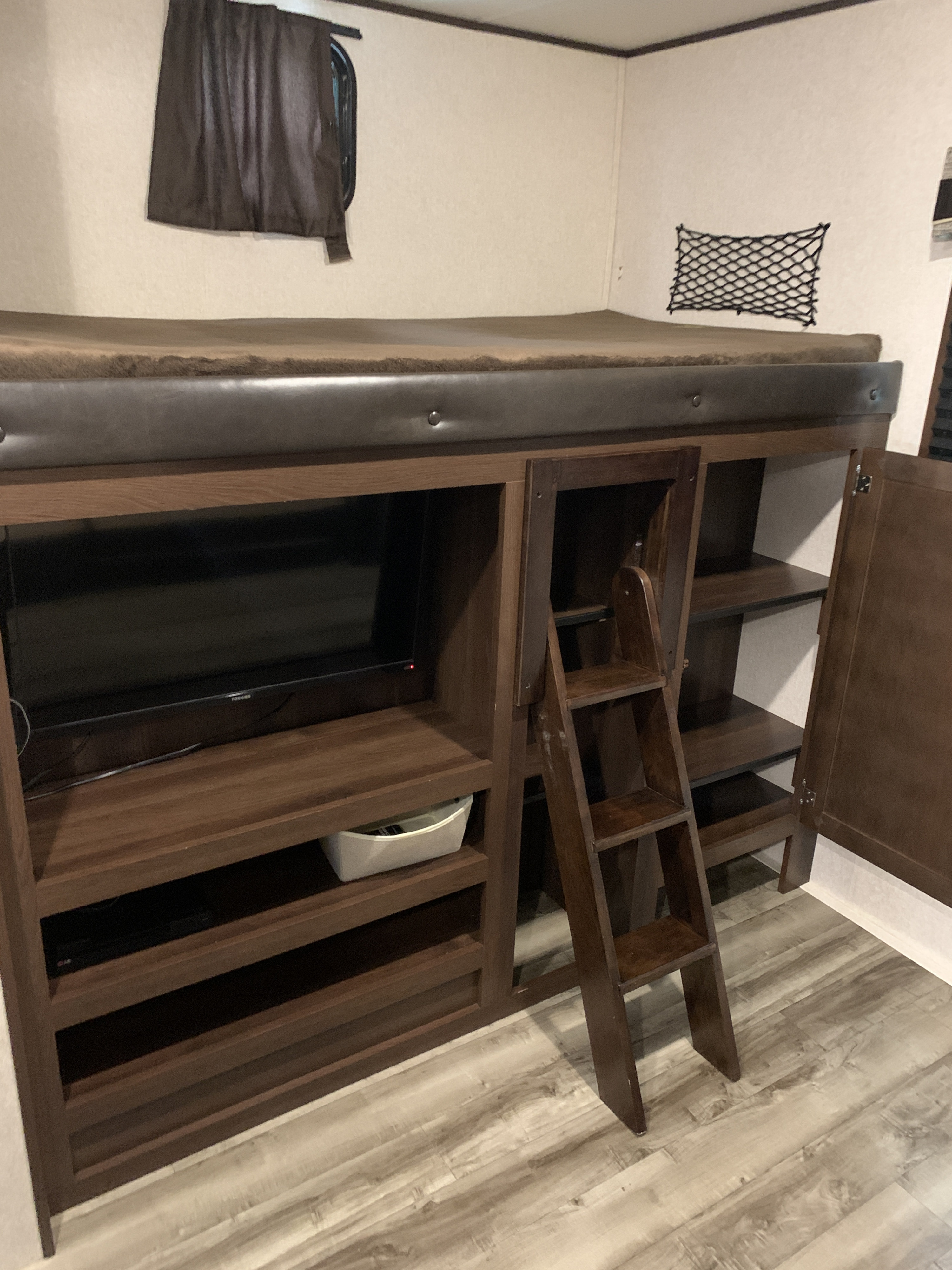 Inside an RV rental: cozy bunk bed with TV, ladder access, built-in storage, and a mesh net for essentials.. Jayco Jay Flight 2019