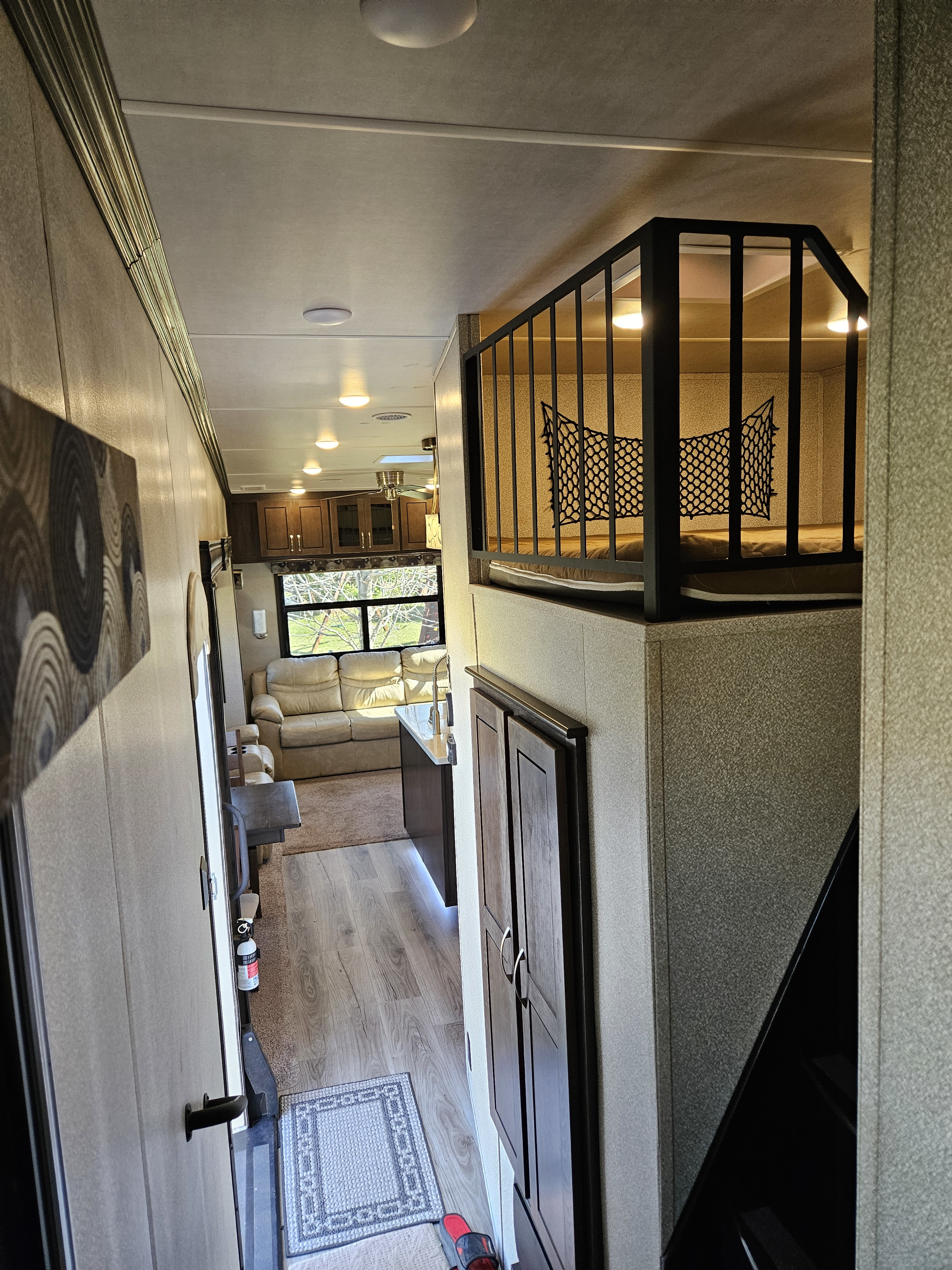Spacious RV rental interior: living area, kitchen, and an elevated loft sleeping space with safety railing and lighting.. Cedar Creek Silverback 2020