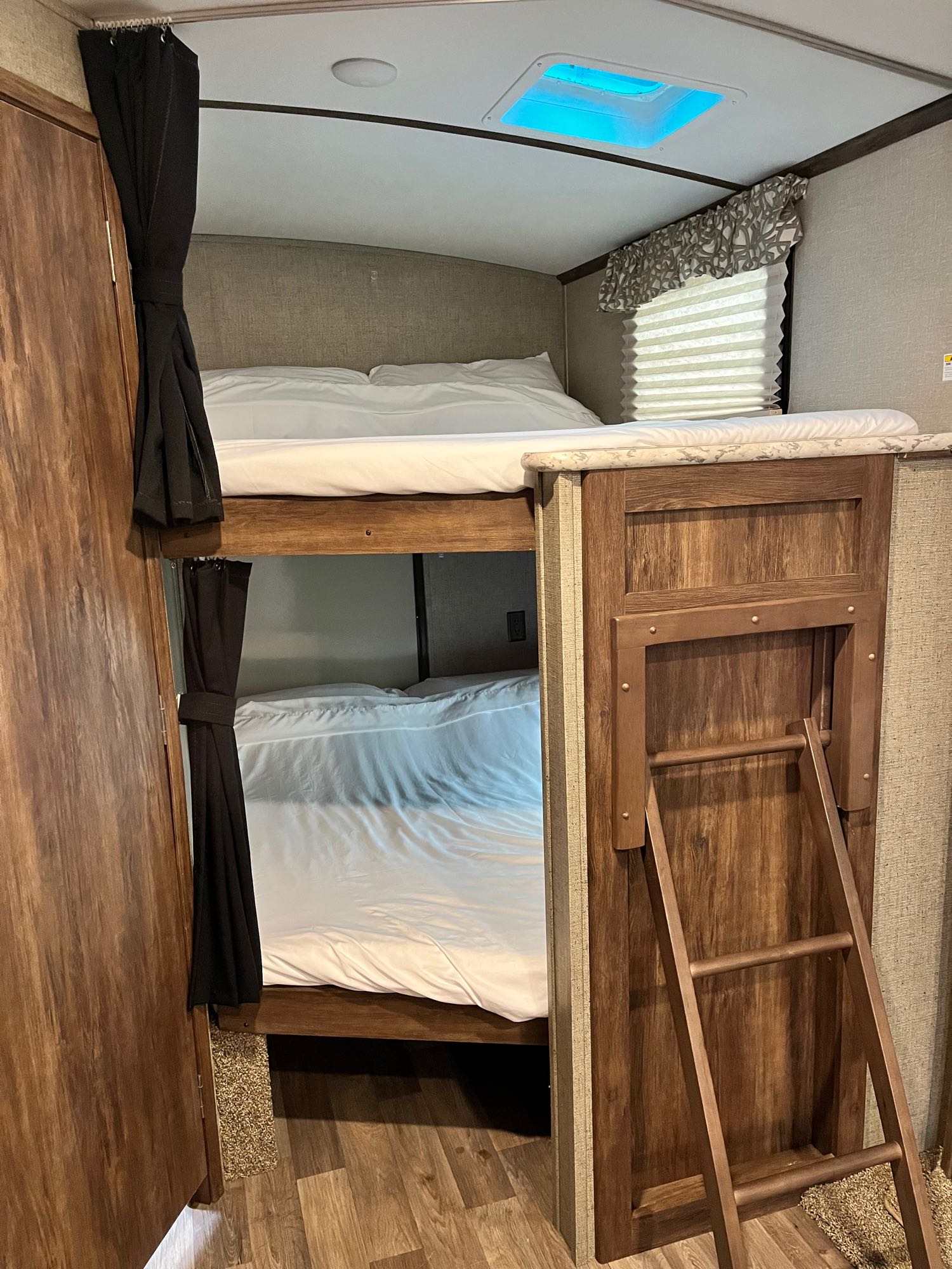 RV rental bunk beds: a neat, space-saving sleeping area with a ladder and privacy curtains, perfect for trips.. Keystone RV Cougar X-Lite 2018