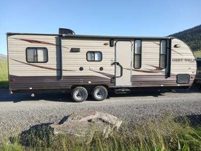 Grey Wolf travel trailer RV rental, parked on gravel. Ideal for camping and outdoor adventures.. Forest River Cherokee Grey Wolf Toy Hauler 2016