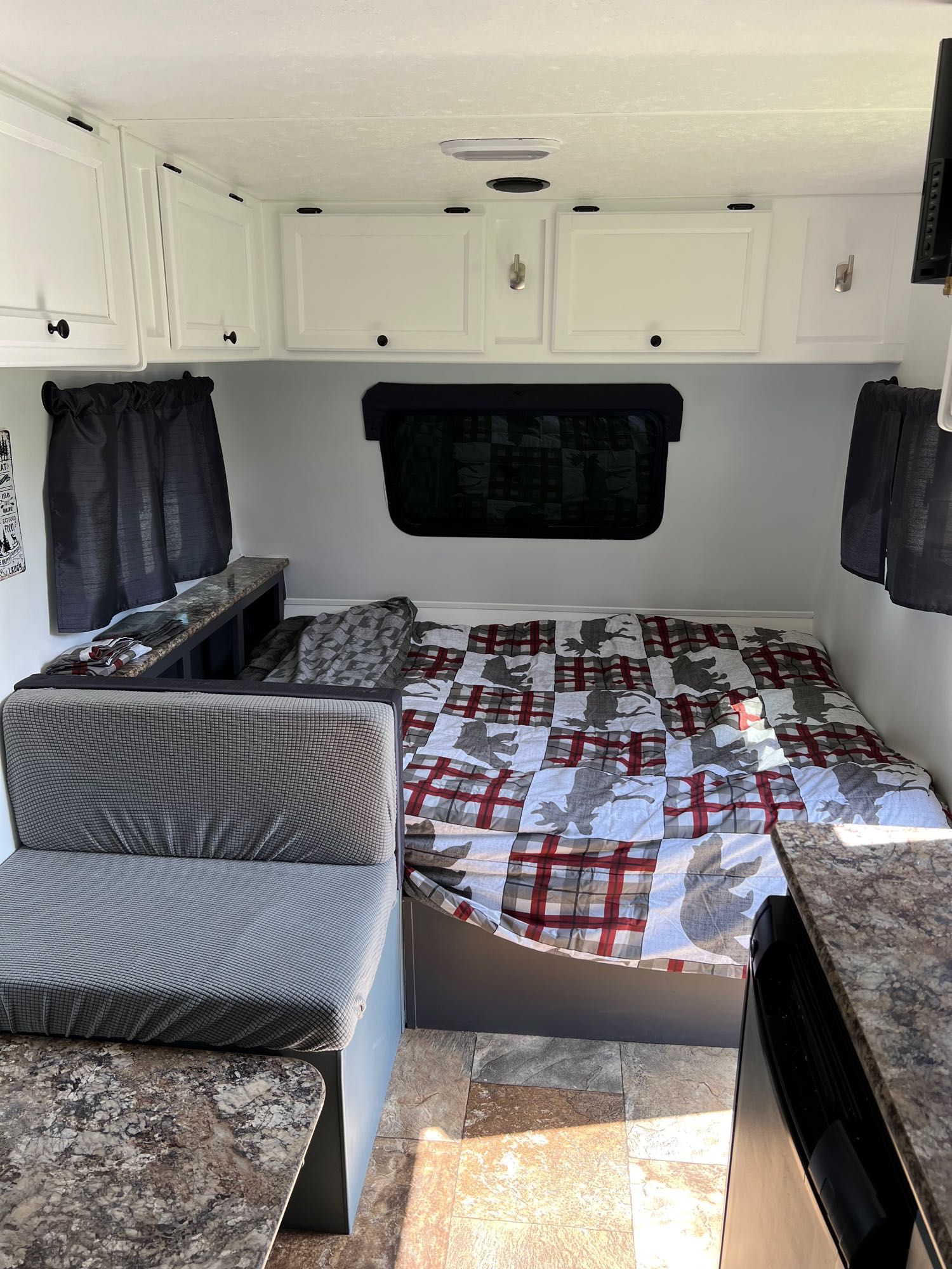 Spacious RV rental interior: bed with plaid/moose comforter, dinette, white cabinets, speckled counters, tiled floor.. Forest River Viking 2016
