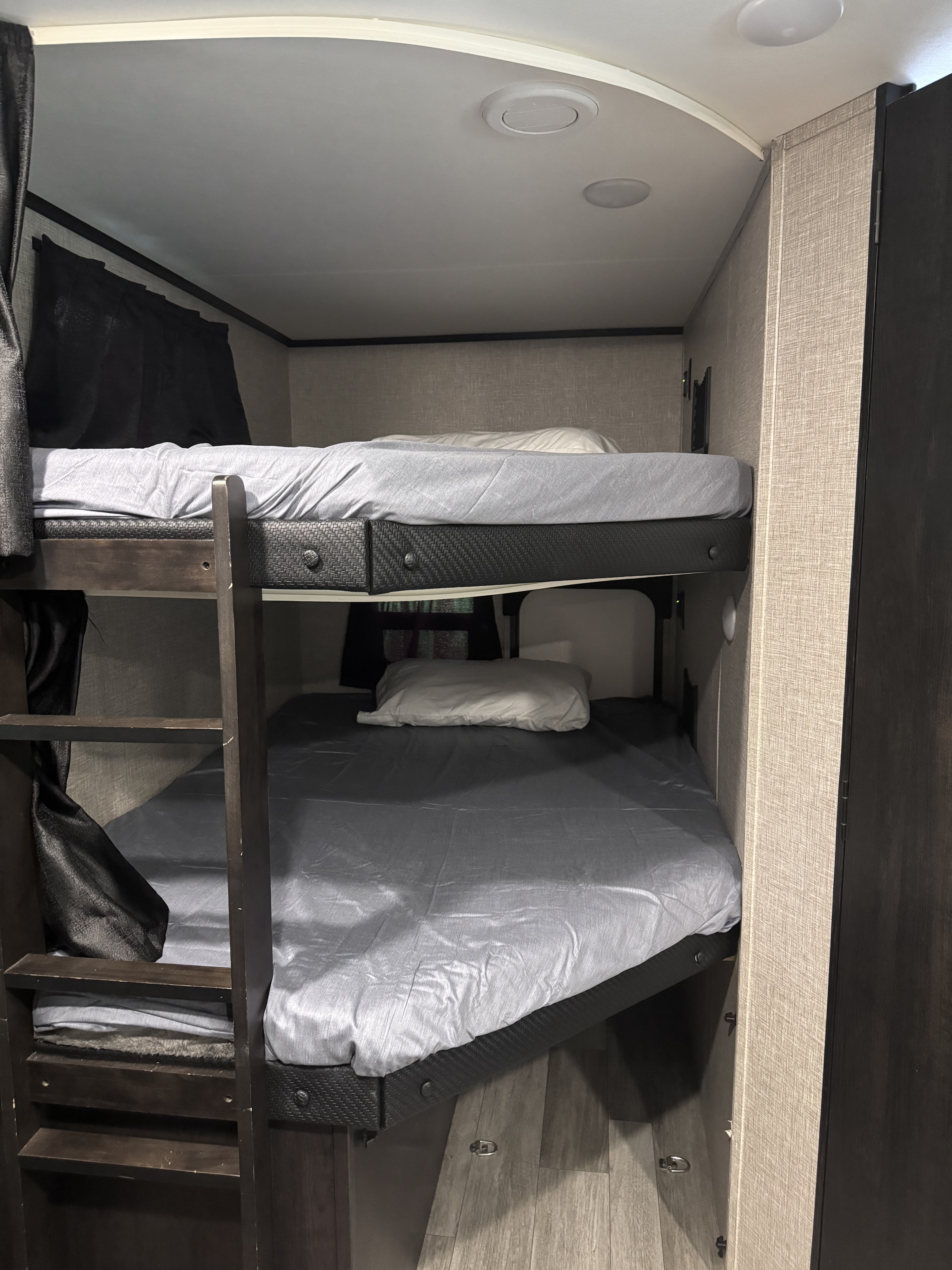 RV rental bunk beds: A cozy sleeping area with two beds, a ladder, and interior lighting in a camper.. Jayco Jay Feather 2023