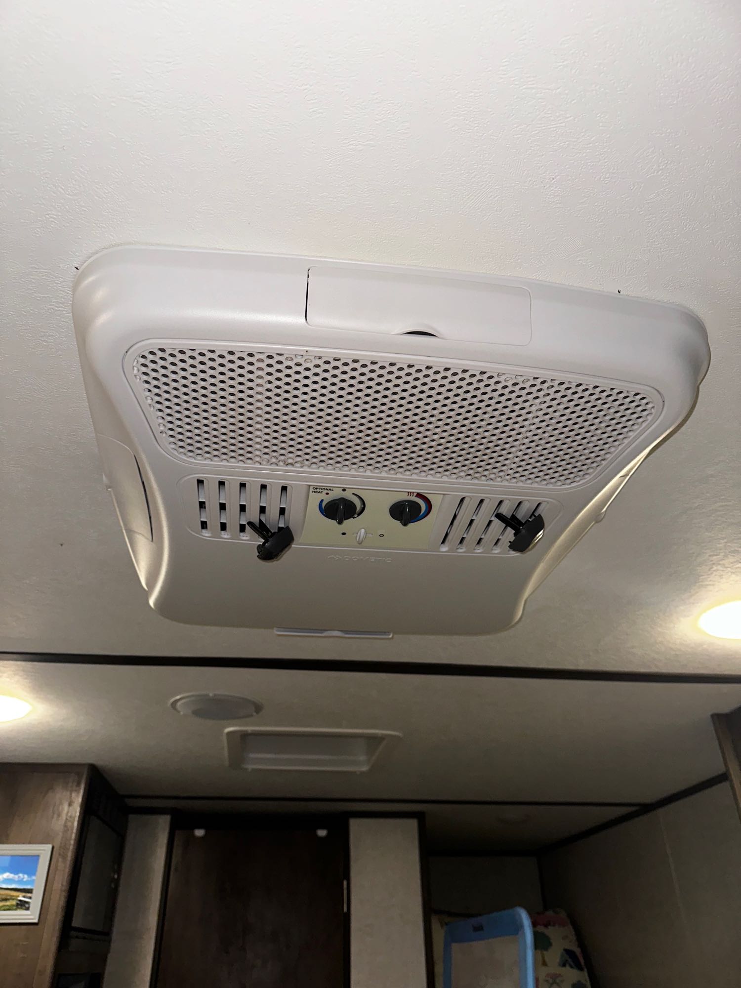 White ceiling-mounted RV rental climate control unit with adjustable vents and control knobs for heating/cooling.. Dutchmen Coleman Lantern LT 2022