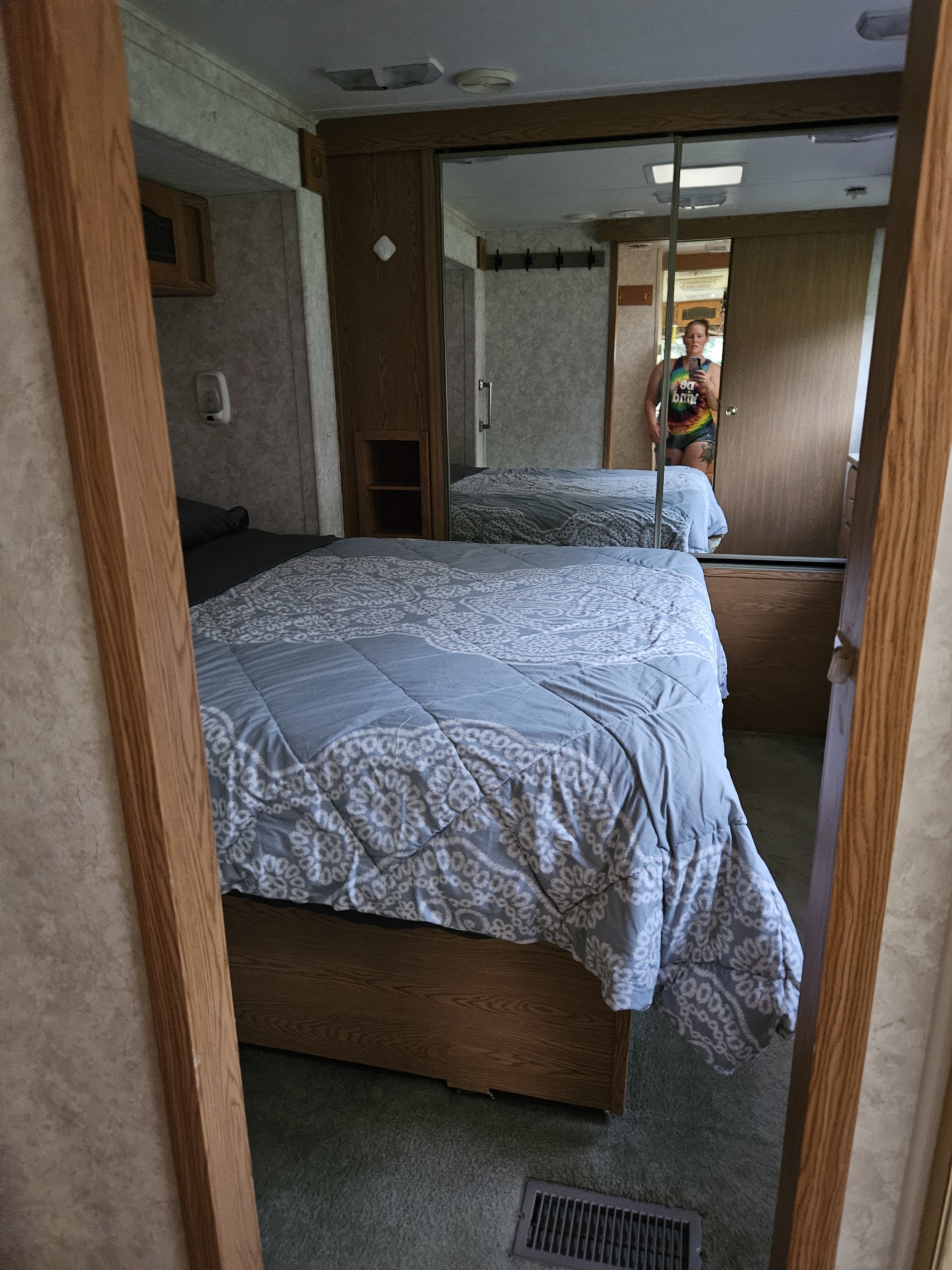 Experience comfort in this RV rental bedroom: a cozy bed with a patterned comforter and mirrored closet reflecting the interior.. Keystone RV Big Sky Montana 2003