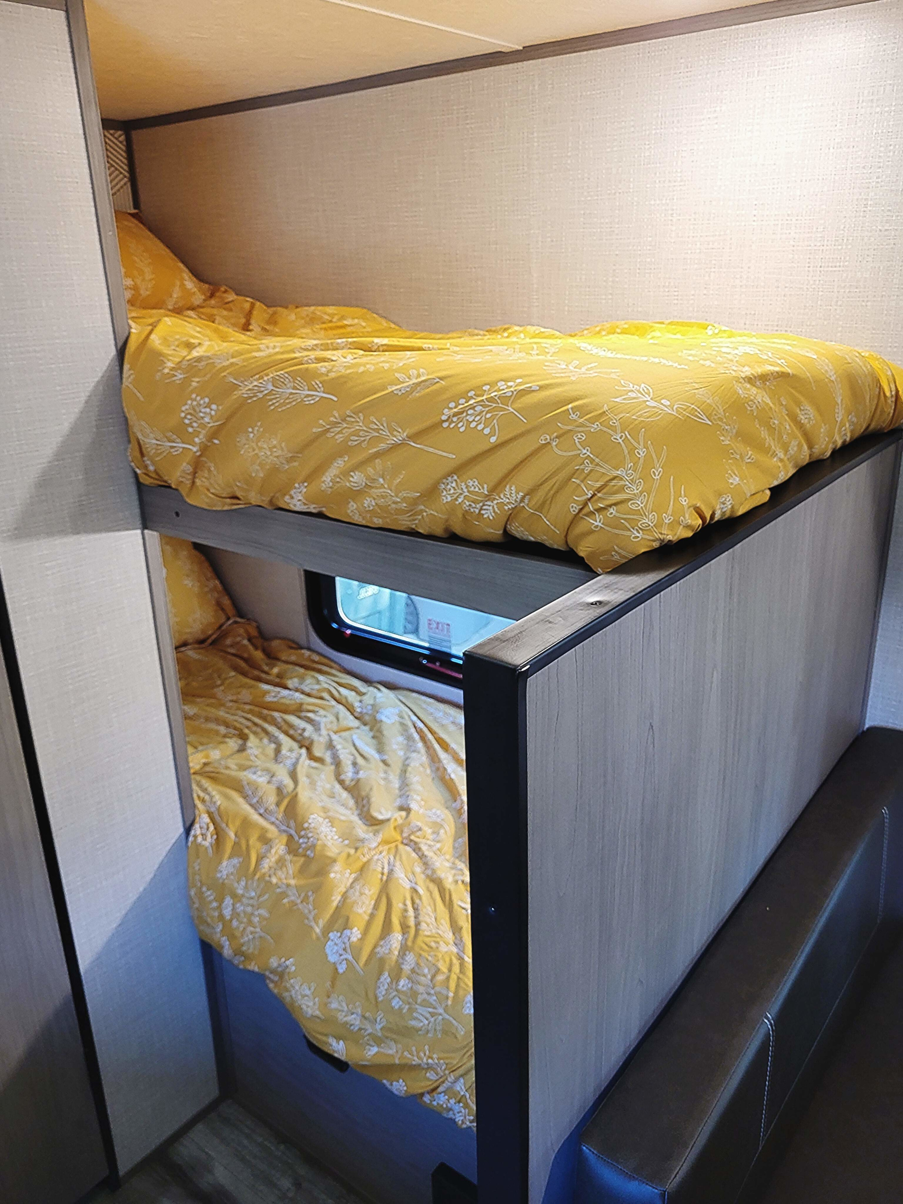 RV rental bunk beds feature cheerful yellow and white floral bedding, creating a cozy sleeping space inside.. Dutchmen Coleman Lantern LT 2023
