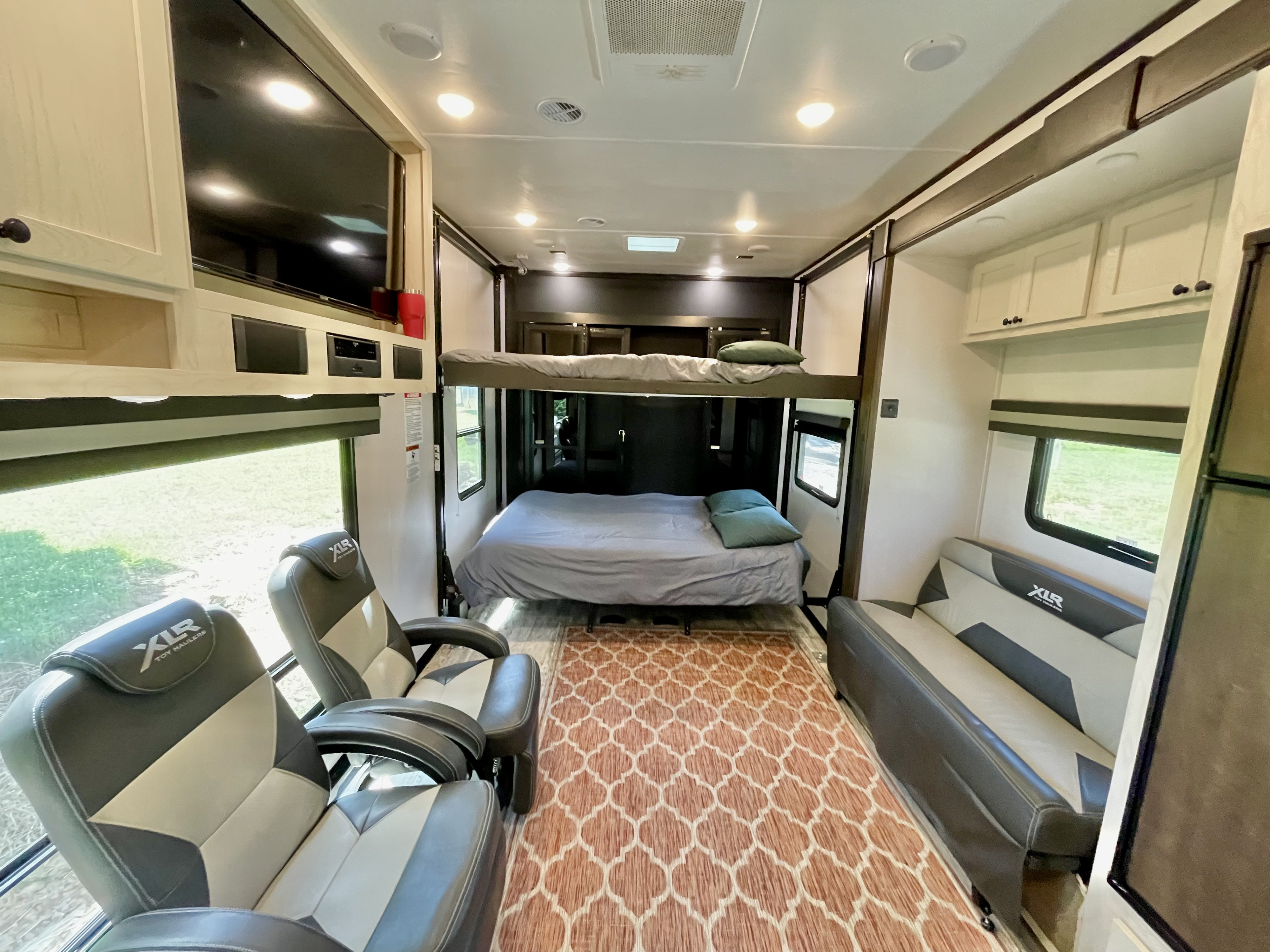 Spacious RV rental interior featuring bunk beds, reclining chairs, and a sofa, perfect for family comfort.. Forest River XLR Nitro Toy Hauler 2022