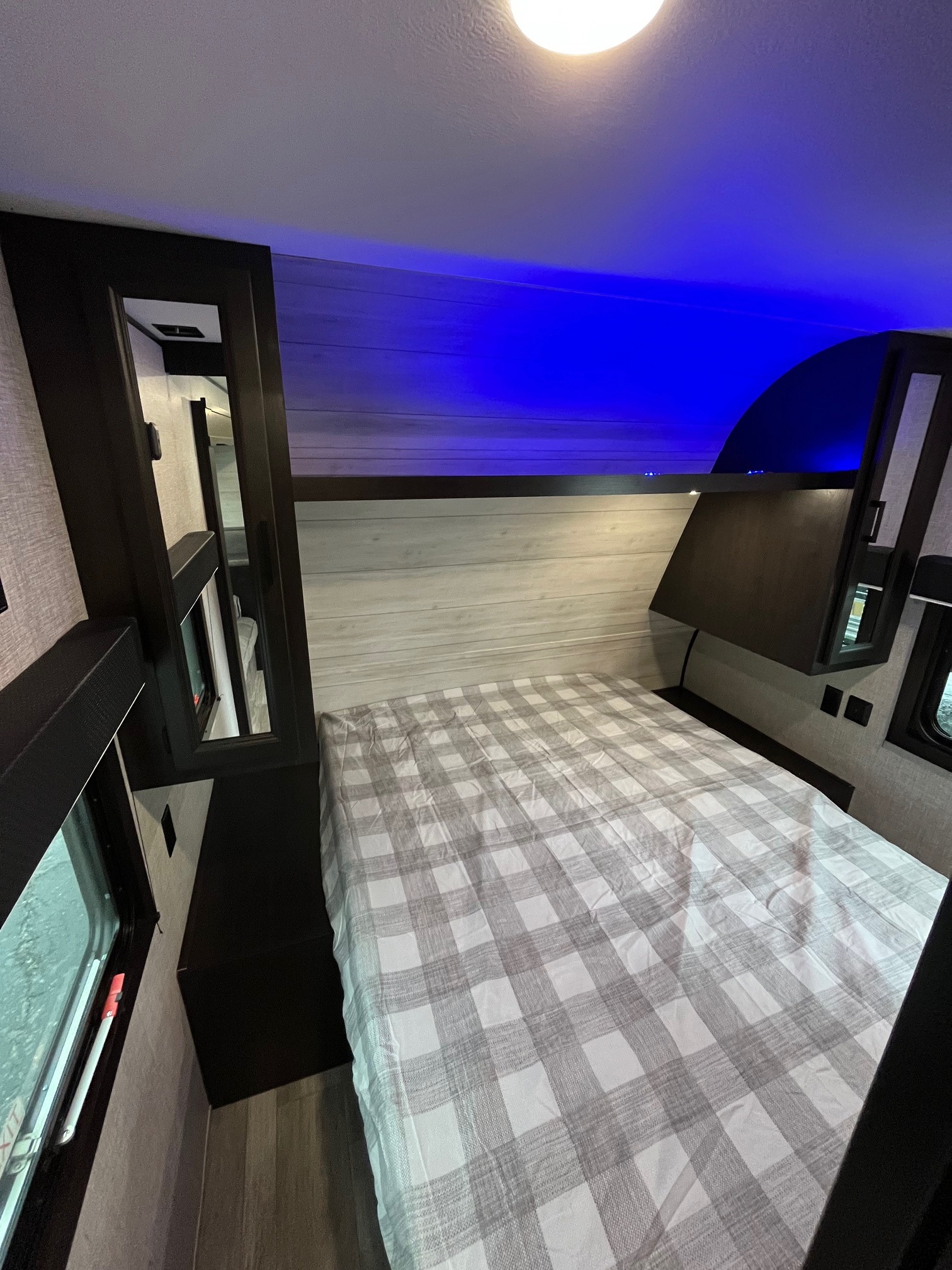 Modern RV rental bedroom: comfy plaid bed, ambient blue lighting, and built-in storage. Ready for adventure.. Jayco Jay Flight SLX 2022