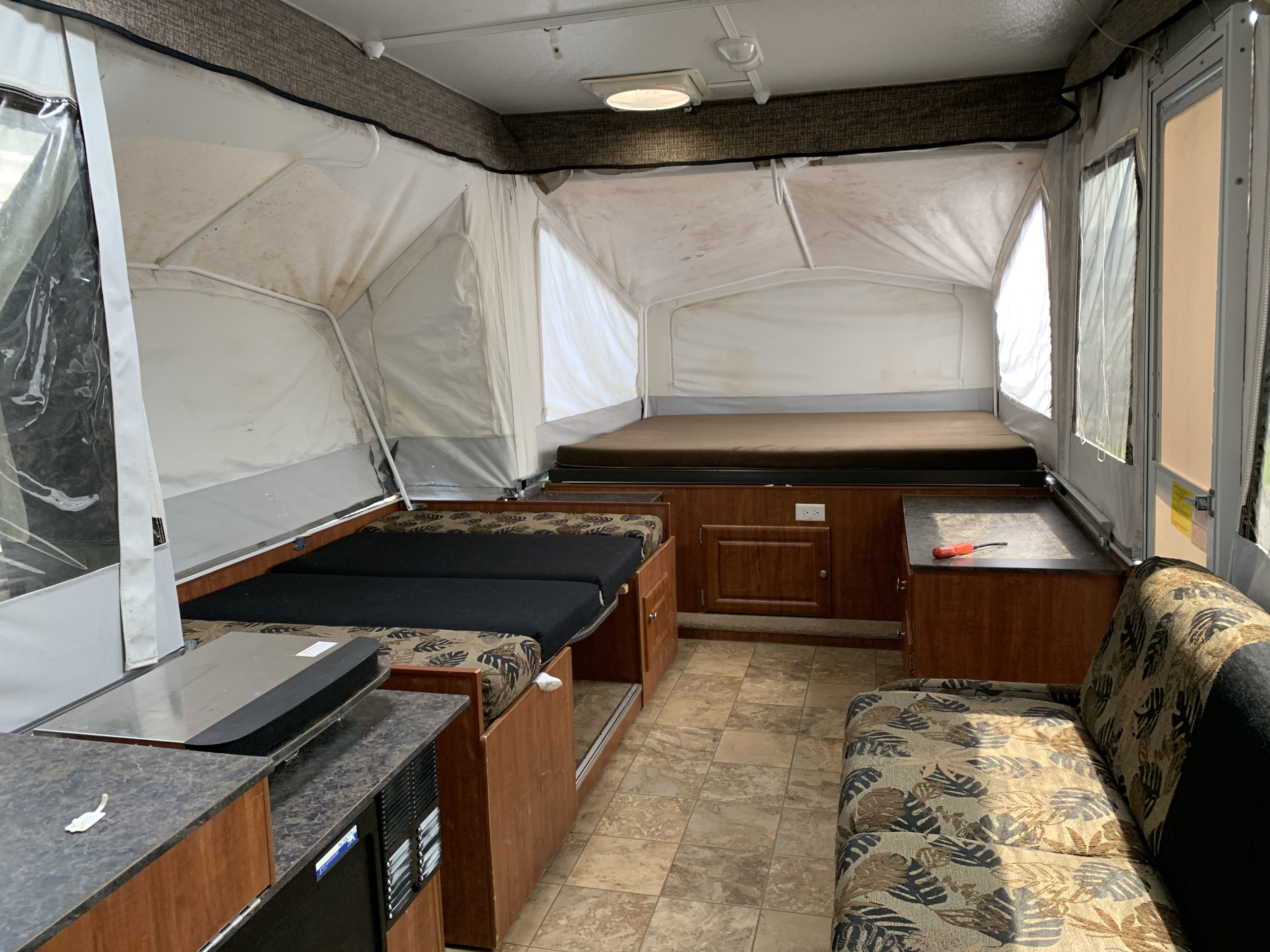 Step inside this cozy RV rental! Pop-up camper interior with extended beds, patterned sofa, and functional cabinets.. Jayco Jay 2012