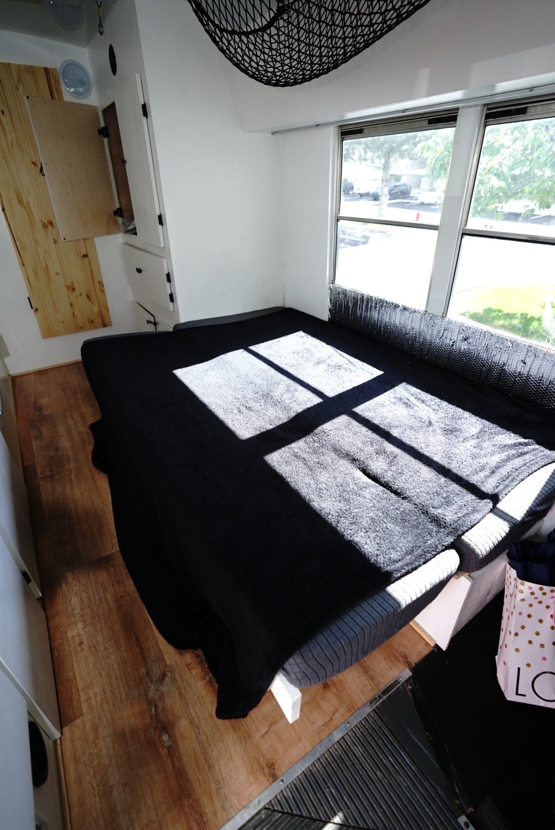 Sunlit RV rental bedroom featuring a comfy bed, ample windows, and wood-paneled storage.. Chevrolet G3500 Express 2006