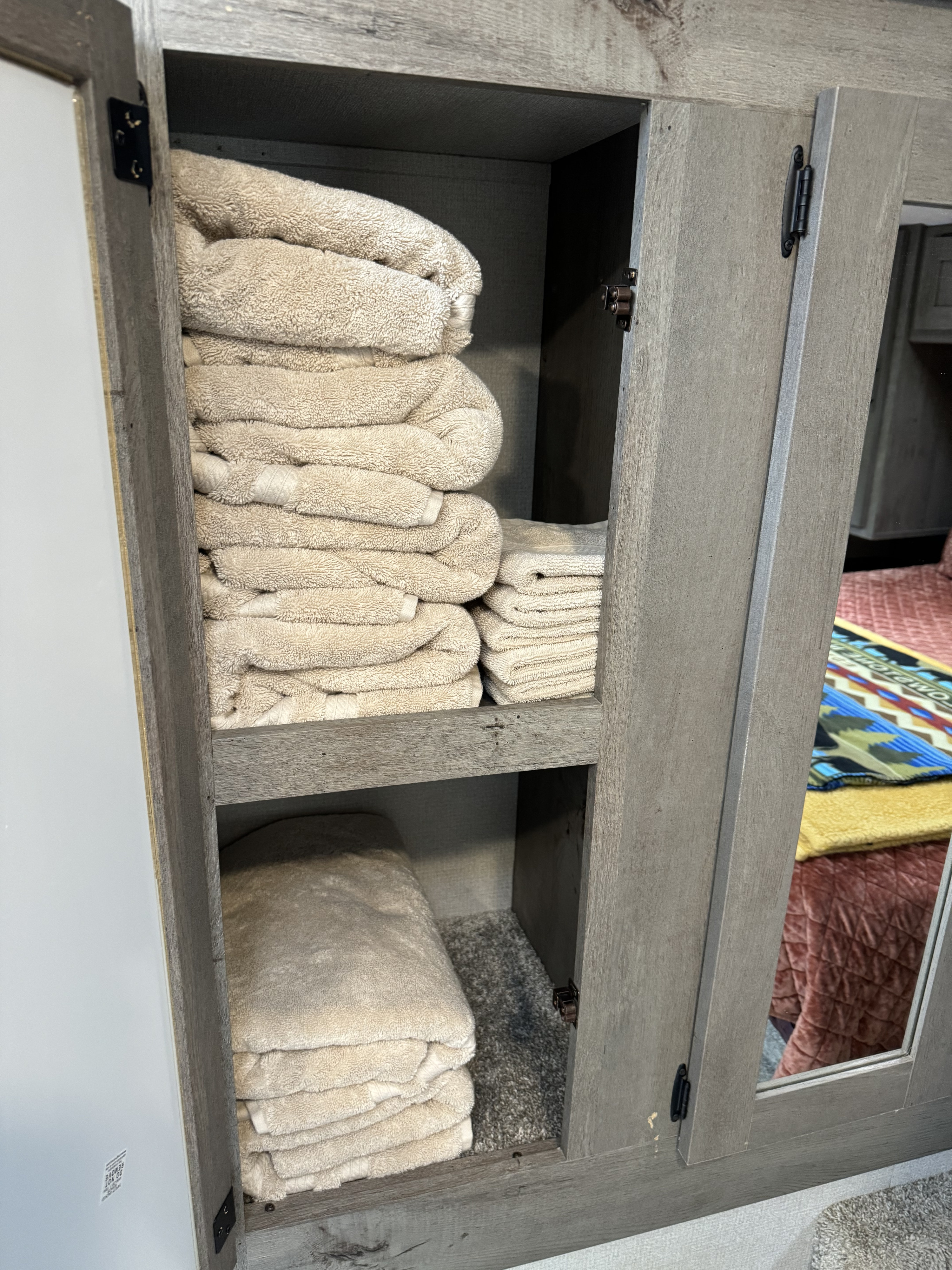 RV rental storage: Neatly folded towels in a wood cabinet with mirrored doors. Essential for comfortable travel.. Keystone Springdale 2021