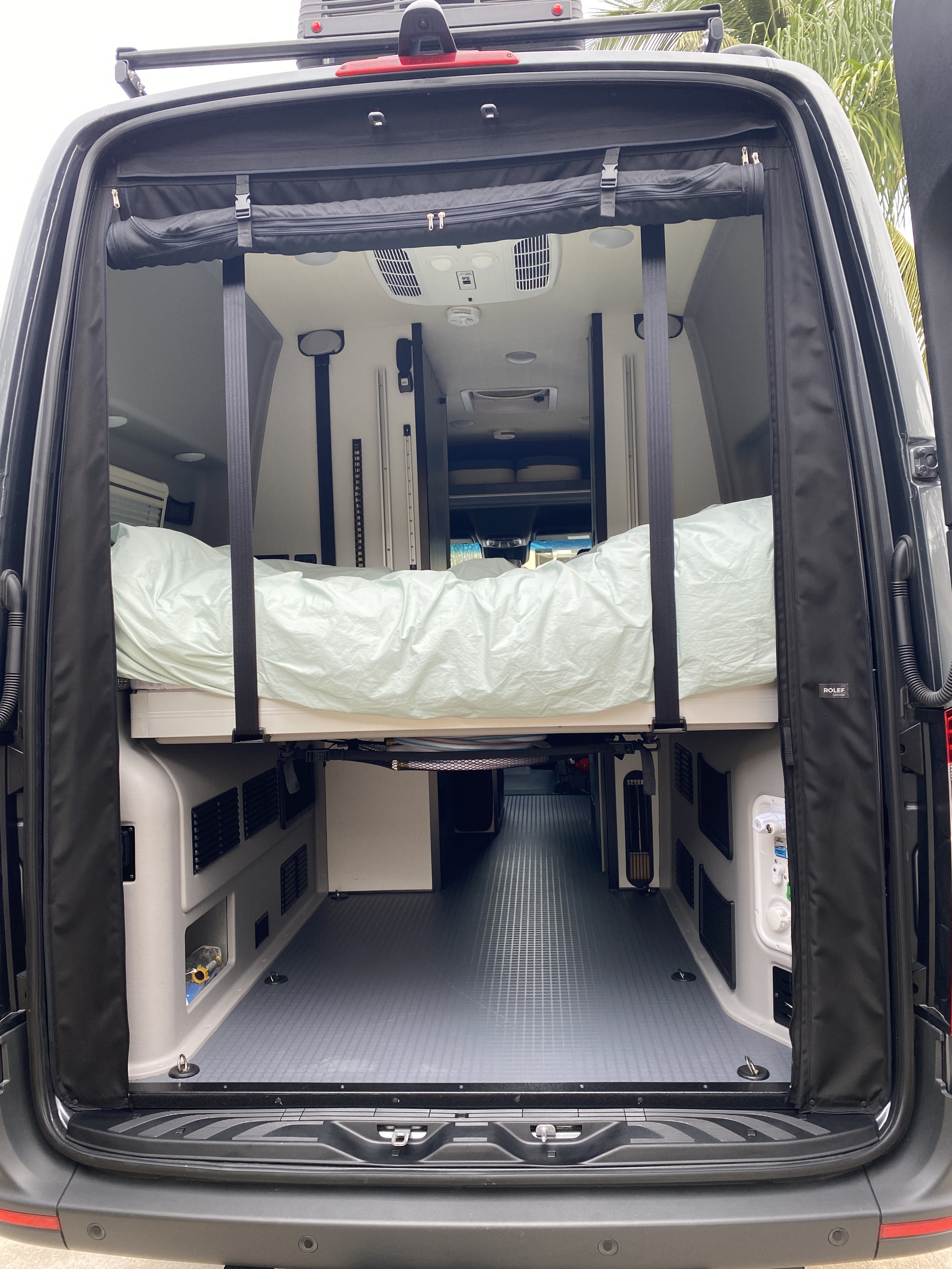 Rear view of an RV rental camper van, revealing elevated bed, gear storage, and functional interior for adventure.. Winnebago Revel 2023