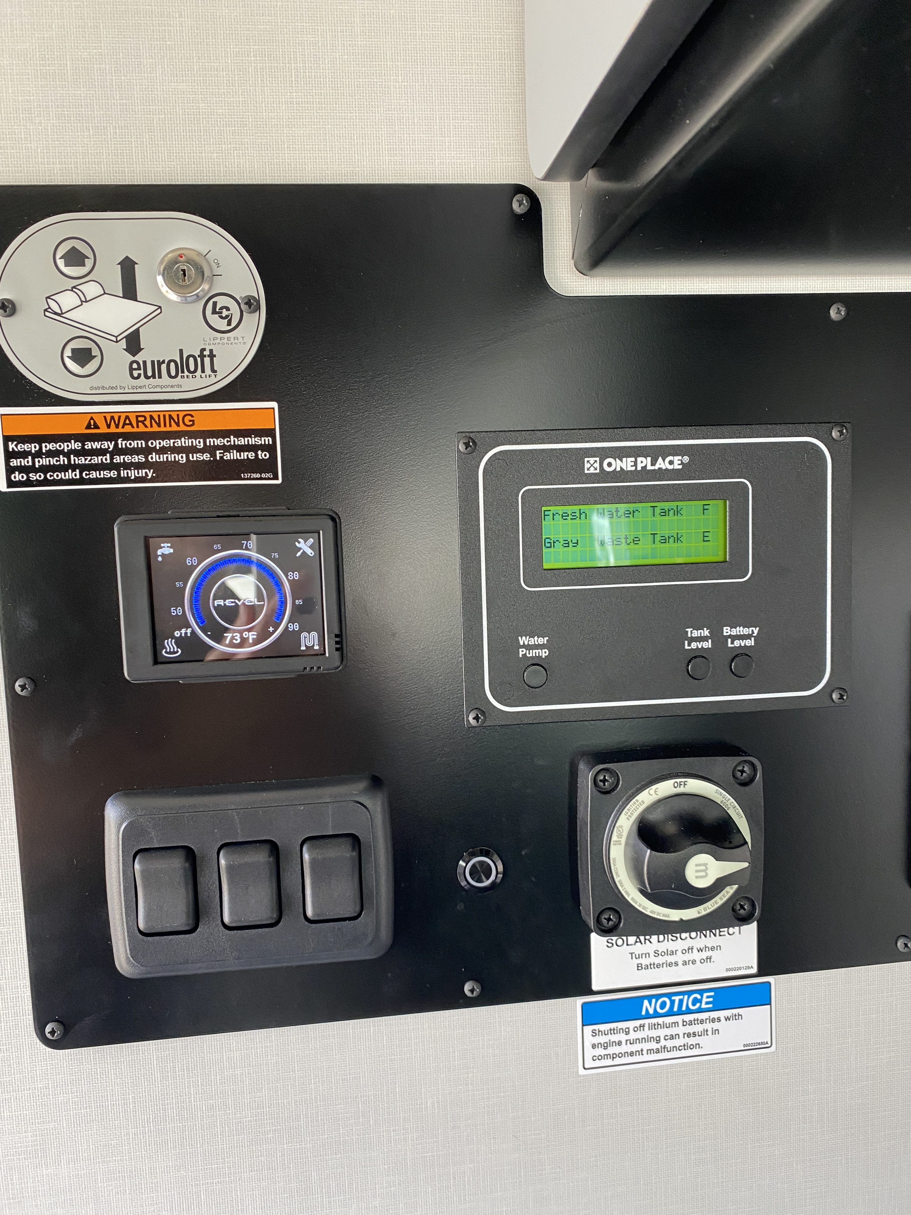An RV rental control panel features a bed lift, climate control, water tank & battery monitor, and power switches.. Winnebago Revel 2023