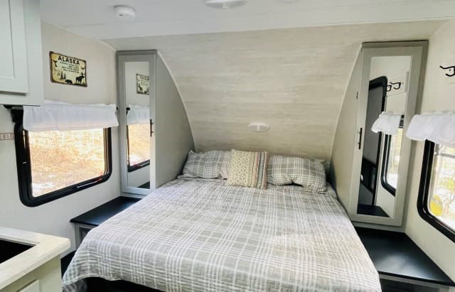 Comfortable RV rental bedroom featuring a queen bed, dual mirrored storage, and scenic windows.. Forest River Vibe 2021