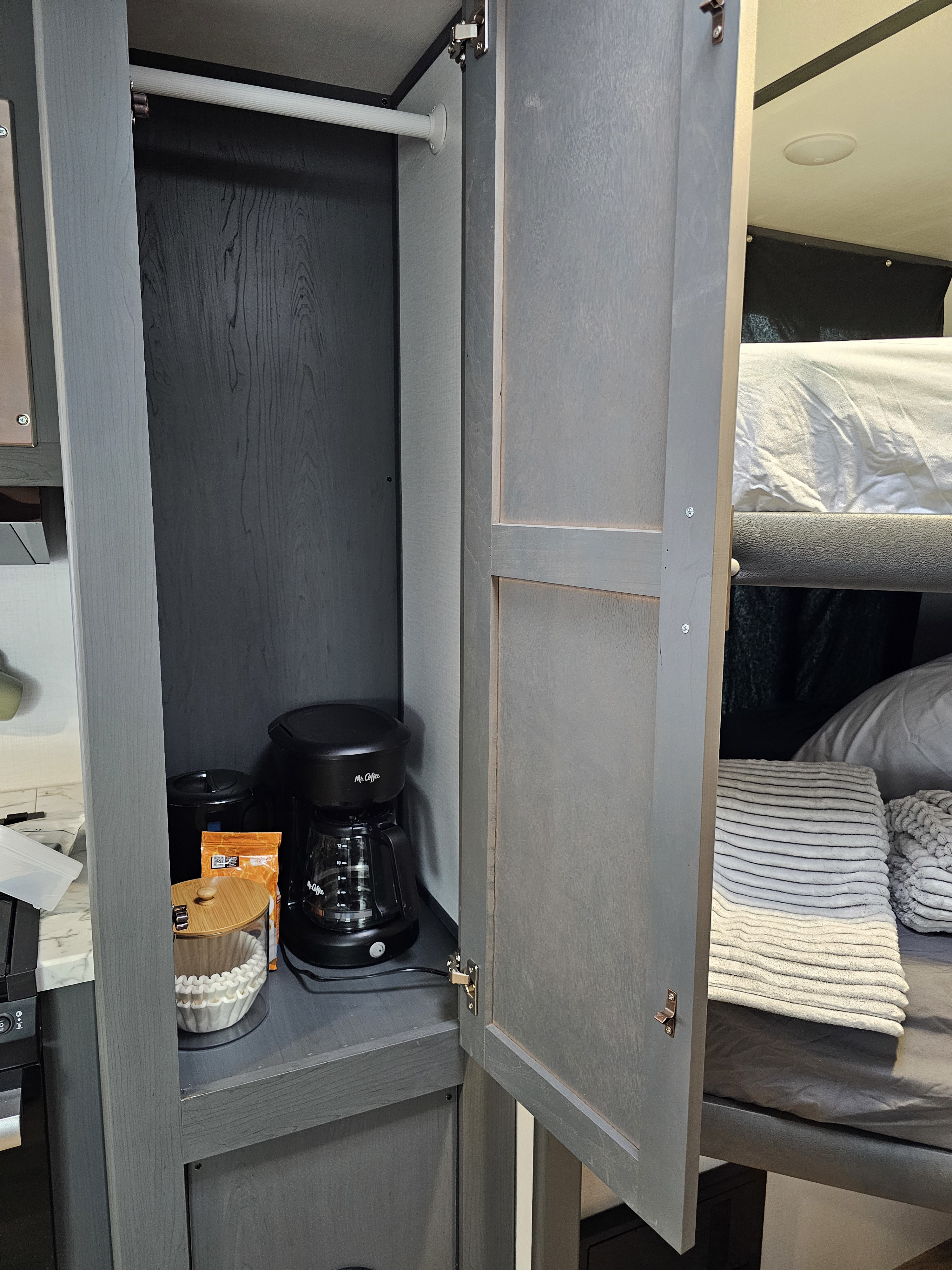 Compact RV rental interior: cabinet with Mr. Coffee maker, filters, and bunk bed visible.. Keystone RV Bullet Crossfire 2023