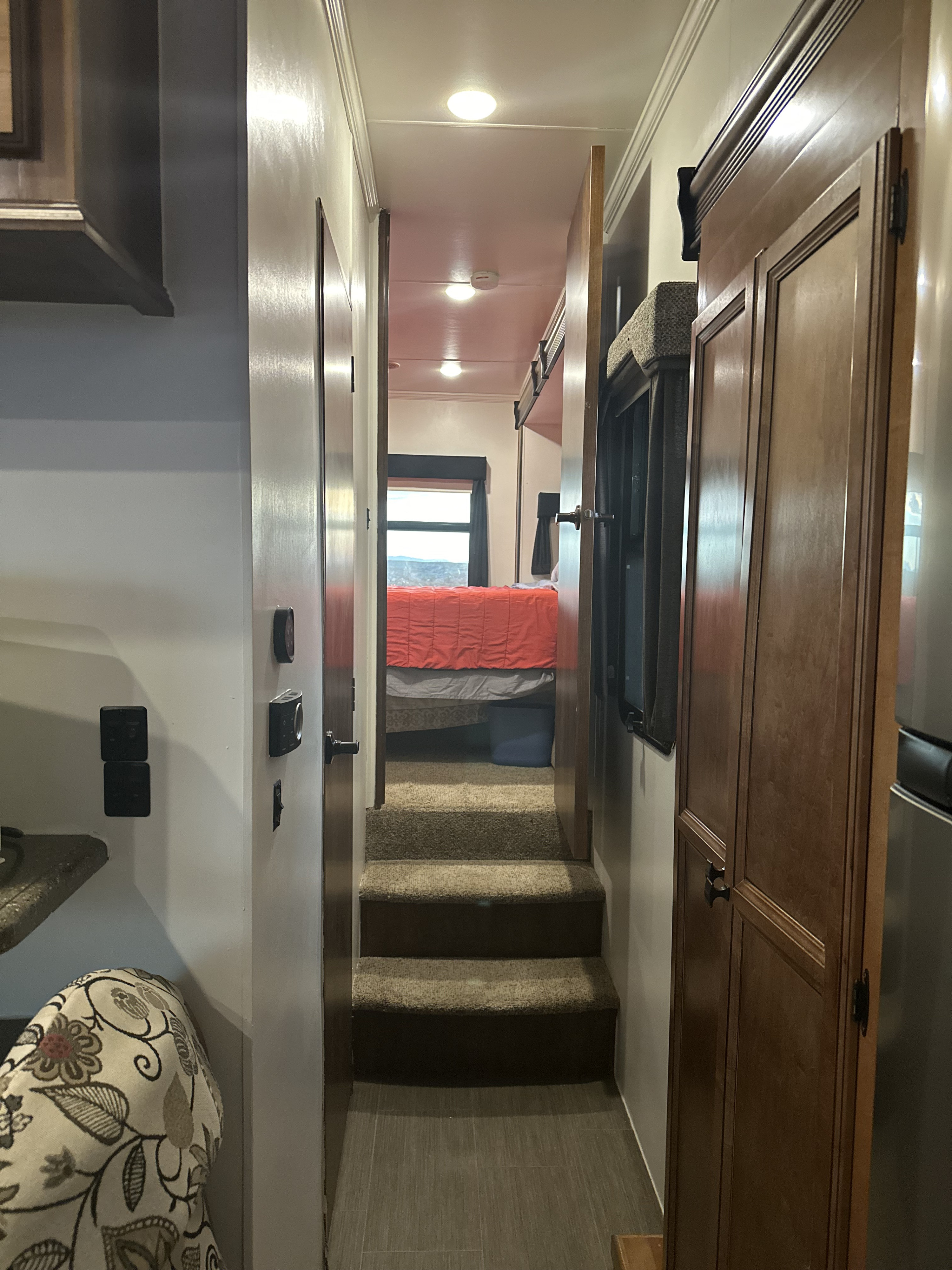 An RV rental interior showing a living area, stairs, hallway, and a bedroom with a window view of mountains.. Heartland RVs Big Country 2016