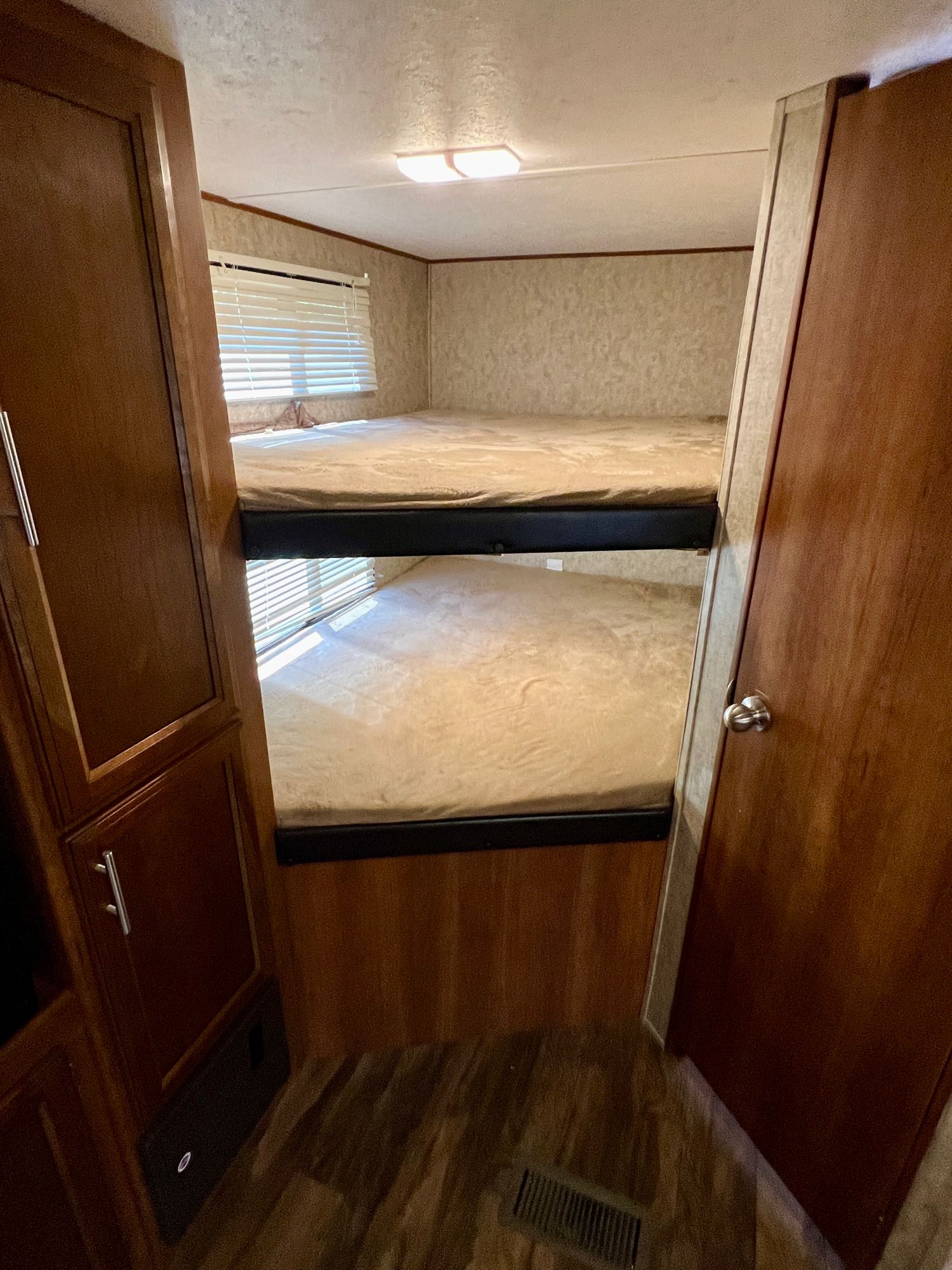 An RV rental's cozy bunk area: two stacked beds, window with blinds, and wood cabinetry for a comfortable stay.. Prime Time Avenger 2018