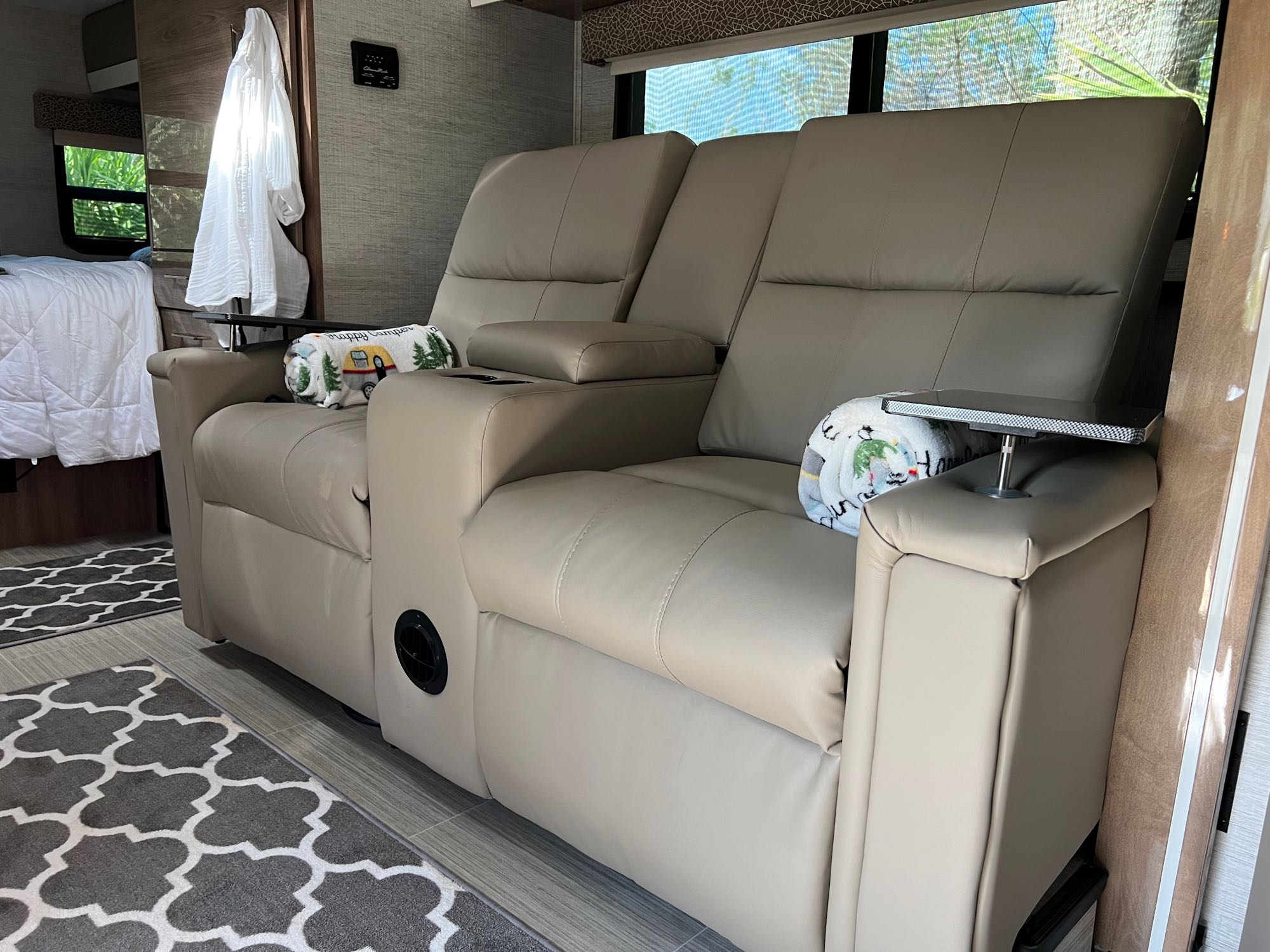 Comfortable RV rental interior: two plush recliners with cupholders, side table, and cozy blankets. Ideal for travel.. Jayco Melbourne Prestige 2021