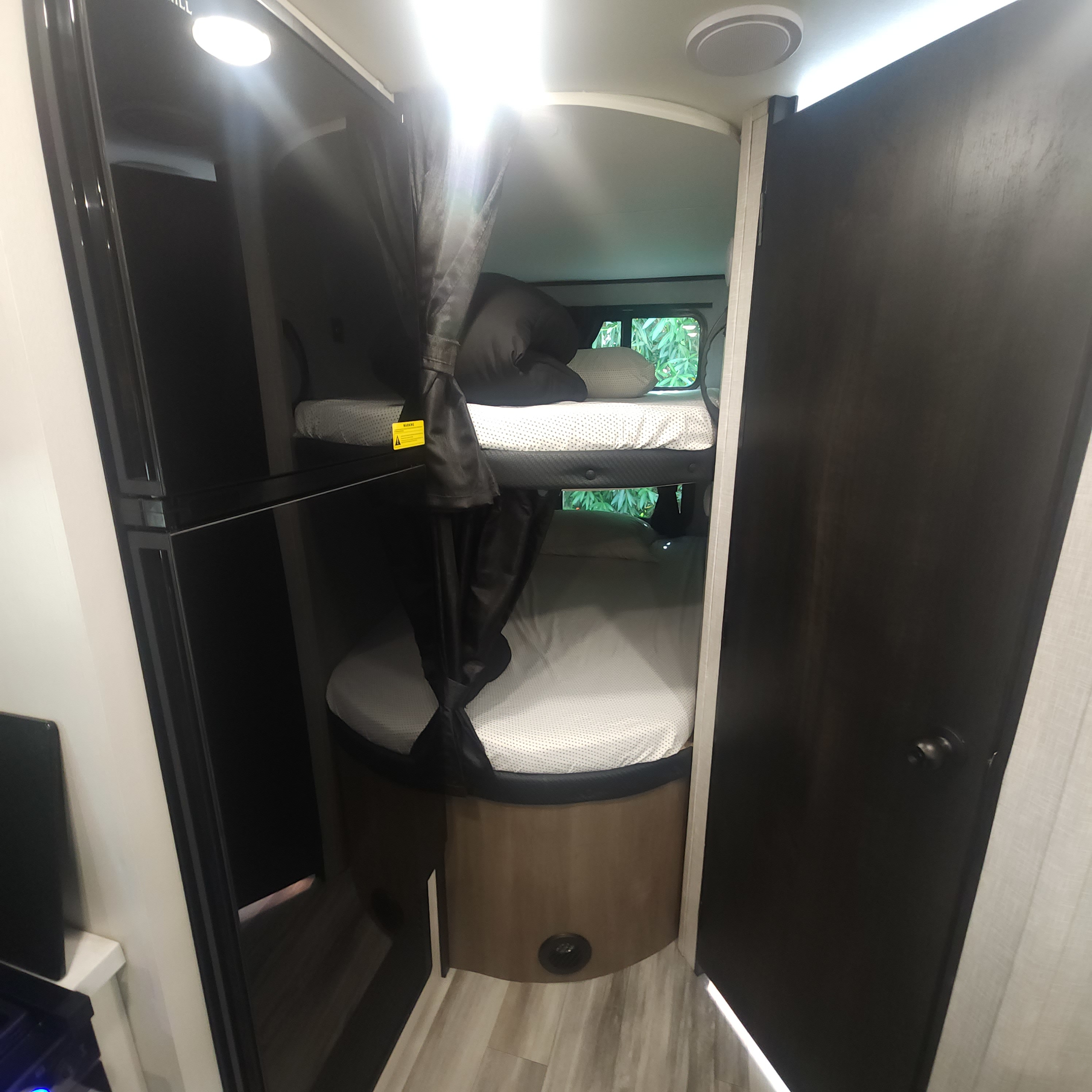 Inside an RV rental, showcasing cozy bunk beds, dark interior accents, and bright lighting, perfect for family travel.. Jayco Jay Flight 2024