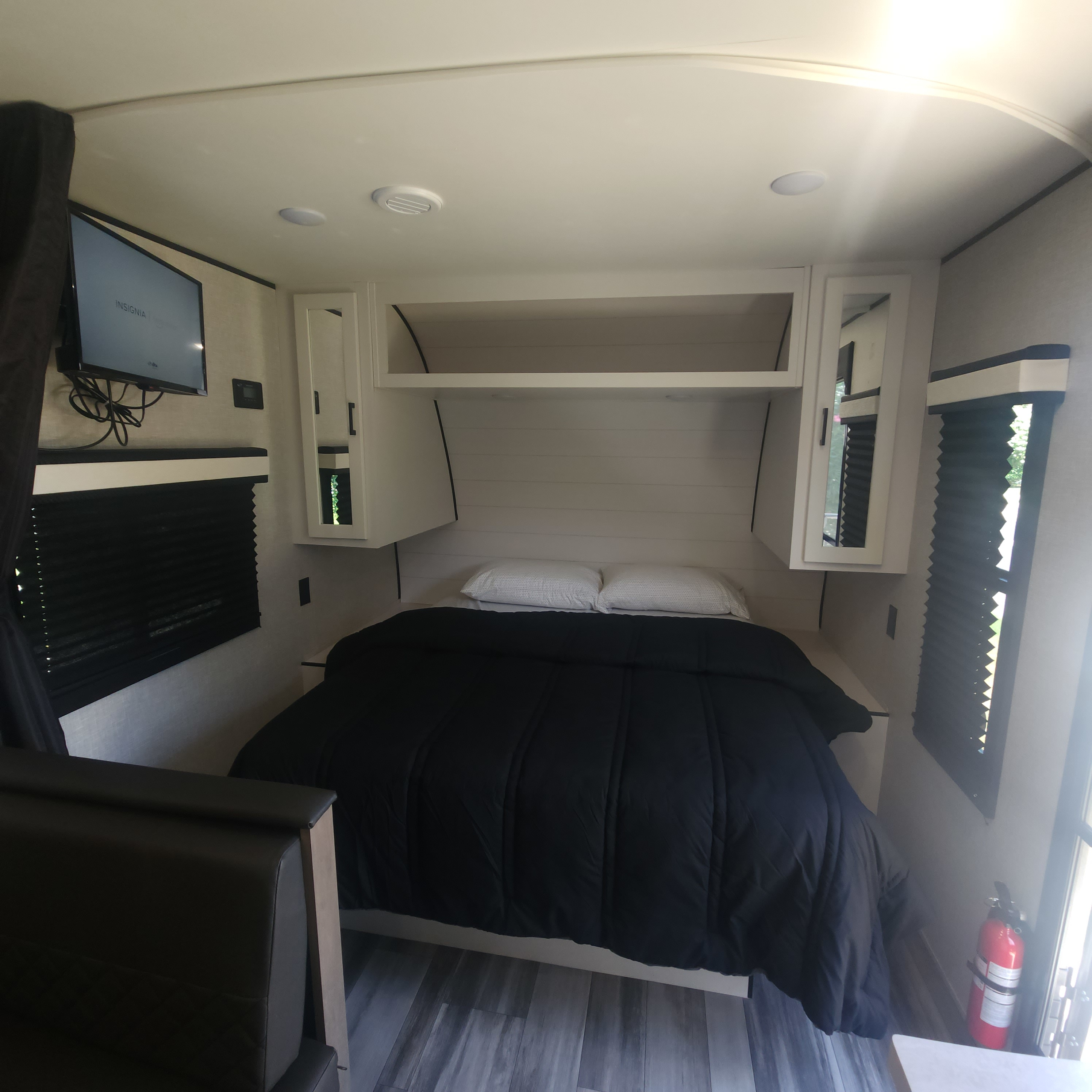Inside this cozy RV rental bedroom, find a comfy bed, white storage cabinets, a mounted TV, and functional window blinds.. Jayco Jay Flight 2024