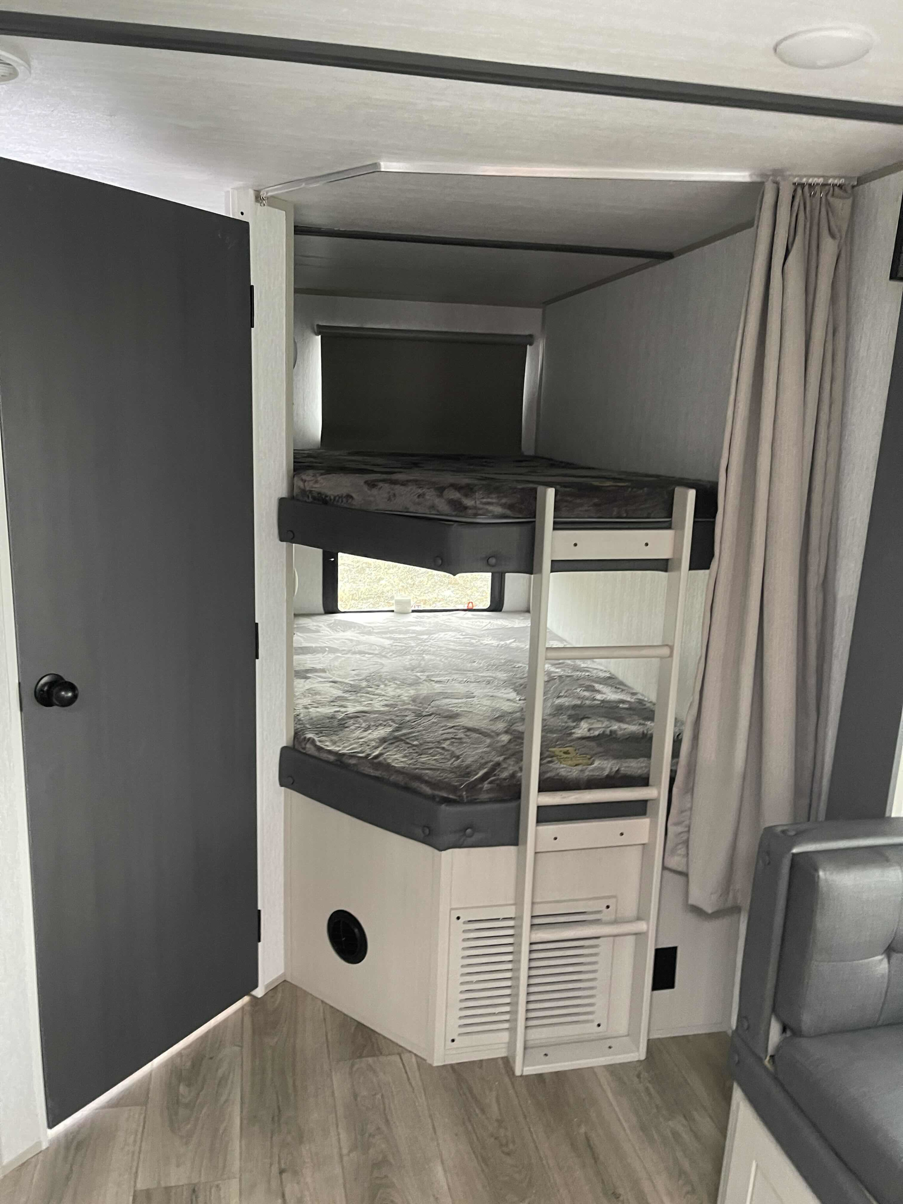 Inside an RV rental: a cozy bunk bed area with a window, ladder, and privacy curtain. Perfect for family adventures.. Forest River Salem Hemisphere HL 2023