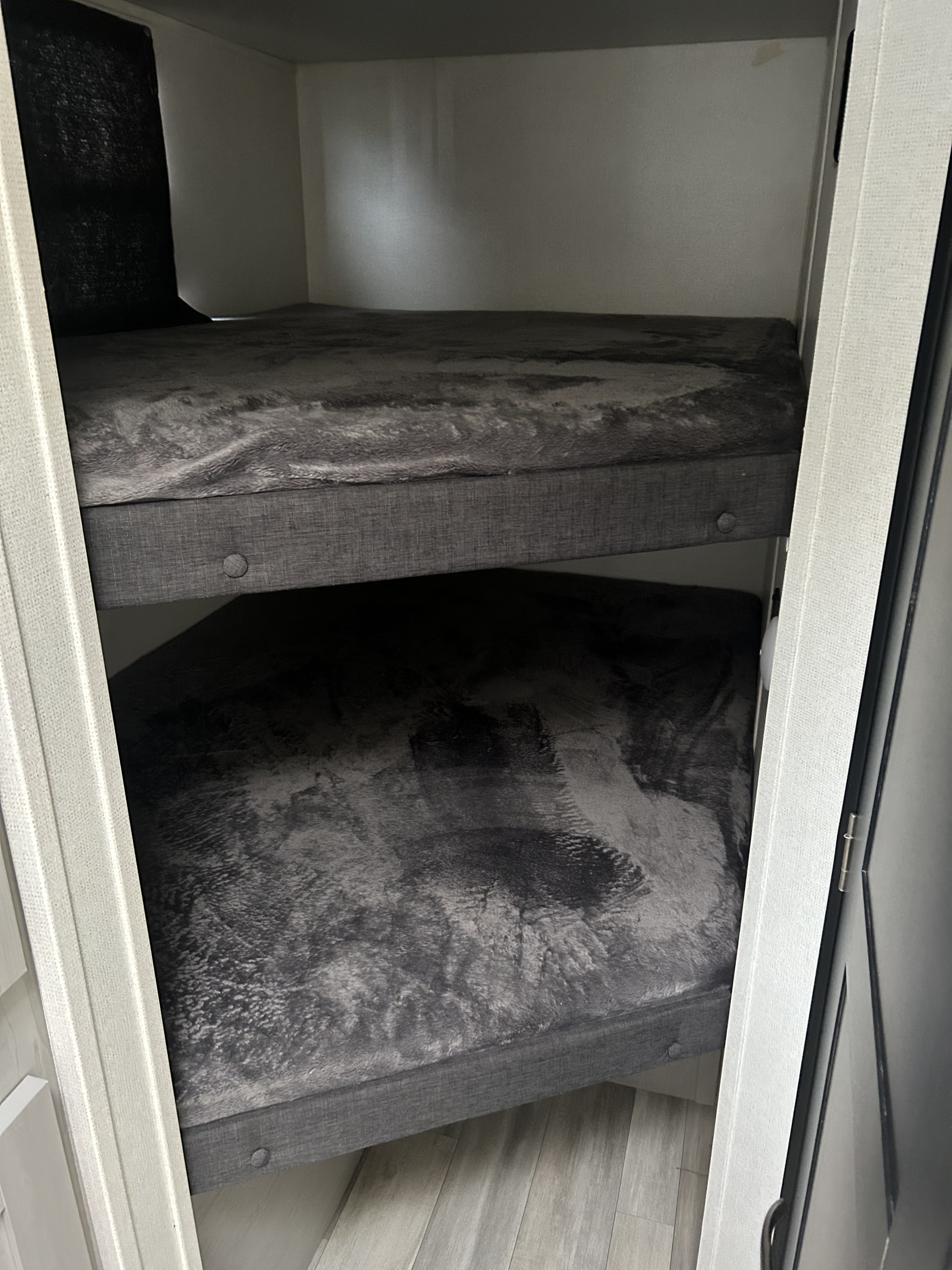 An RV rental's interior shows two stacked gray bunk beds, each with a fluffy blanket, providing a compact sleeping area.. Forest River Tracer LE 2022