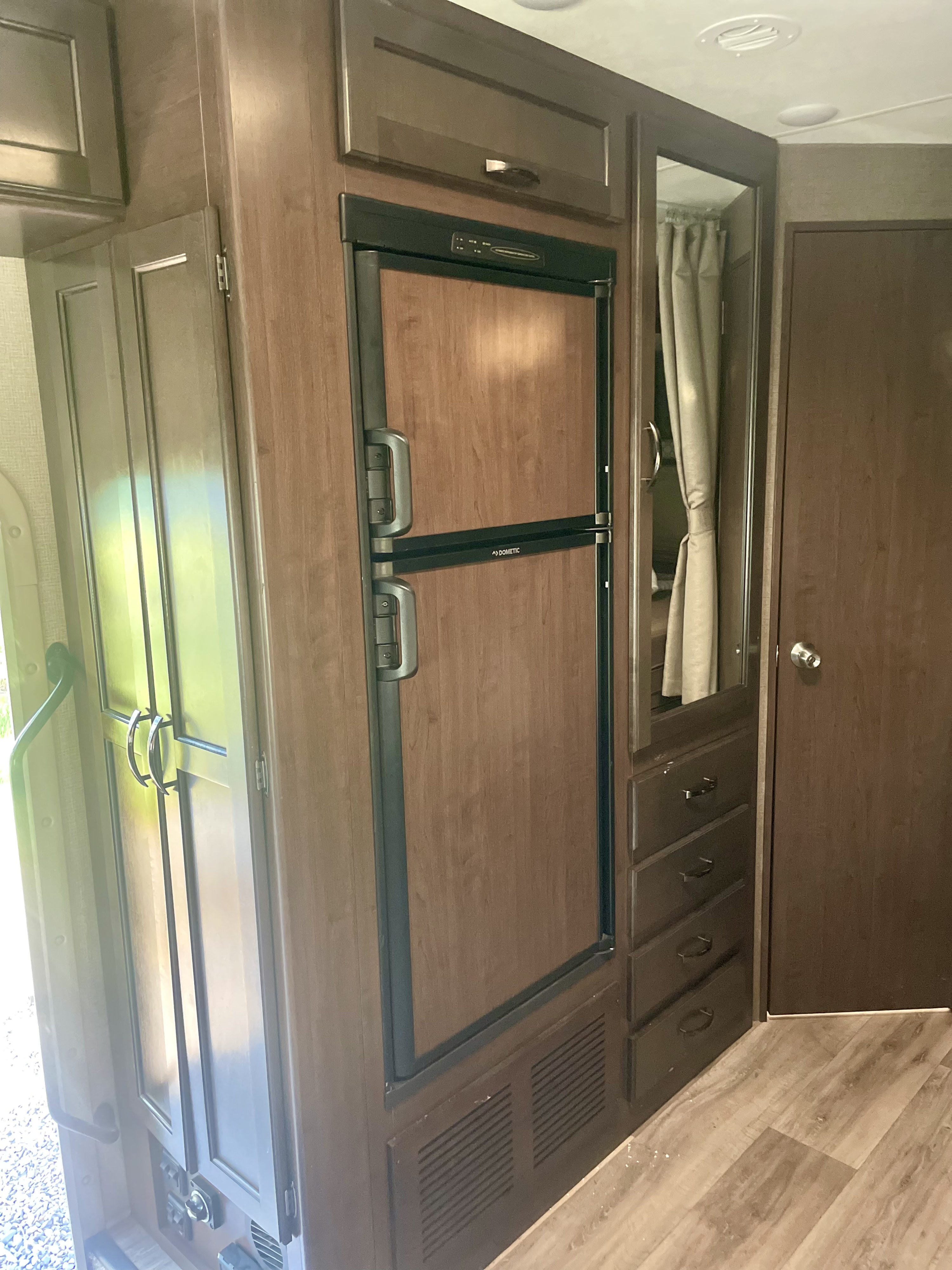 Explore this RV rental: compact interior features a Dometic fridge, wood cabinetry, mirror, and drawer storage.. Thor Freedom Elite 2019