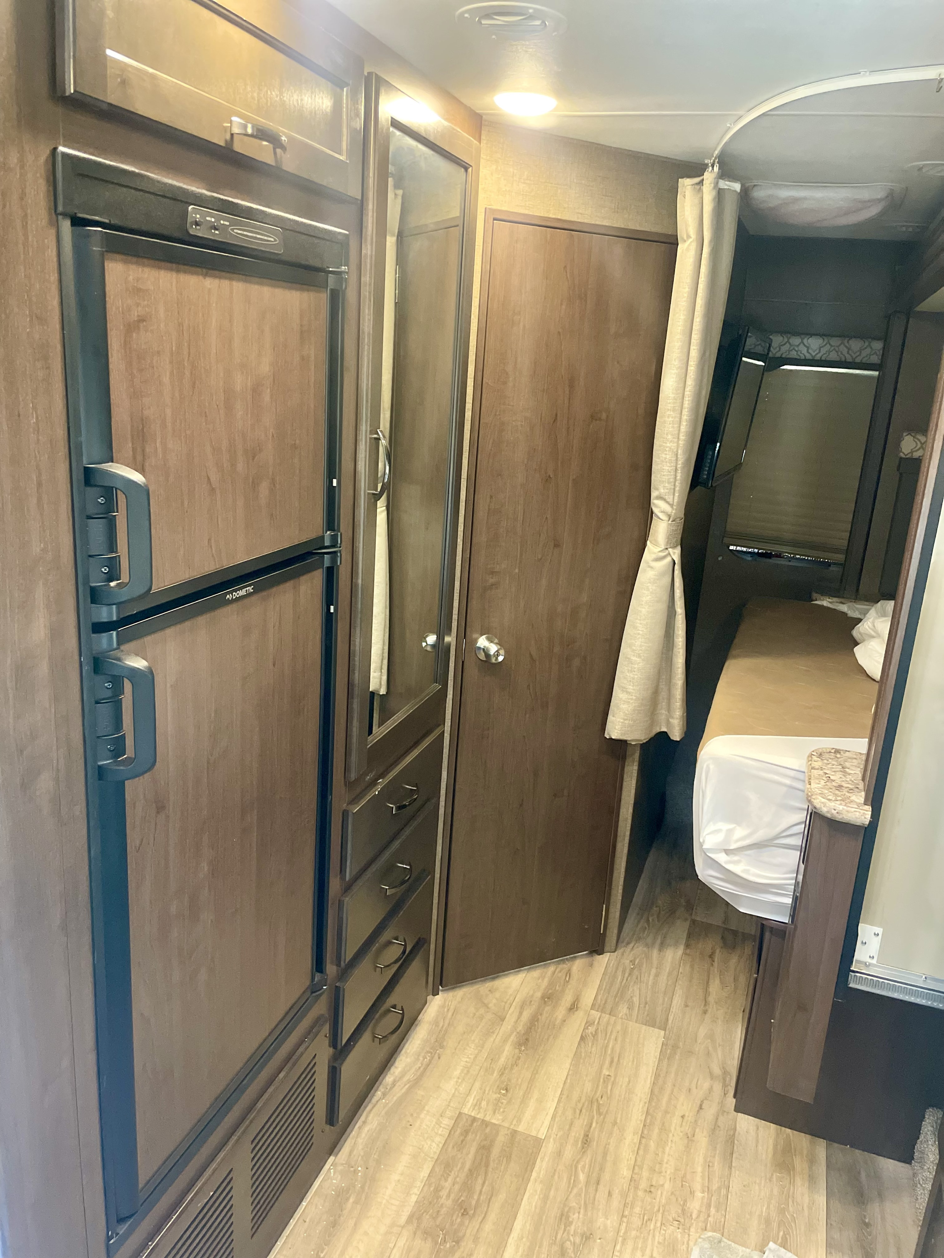 Spacious RV rental interior featuring a Dometic refrigerator, wooden cabinets, and cozy bunk beds. Ideal for adventures.. Thor Freedom Elite 2019